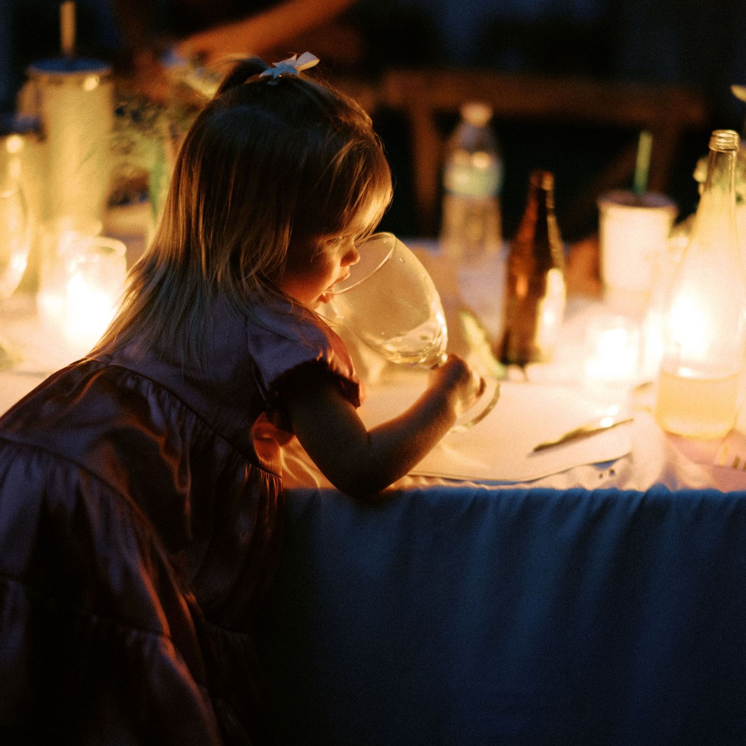 Candlelit wedding reception tables create an intimate ambiance in a dark setting.