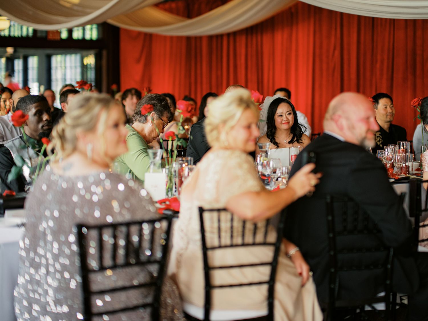 Wedding reception dining room with guests seated at decorated tables.