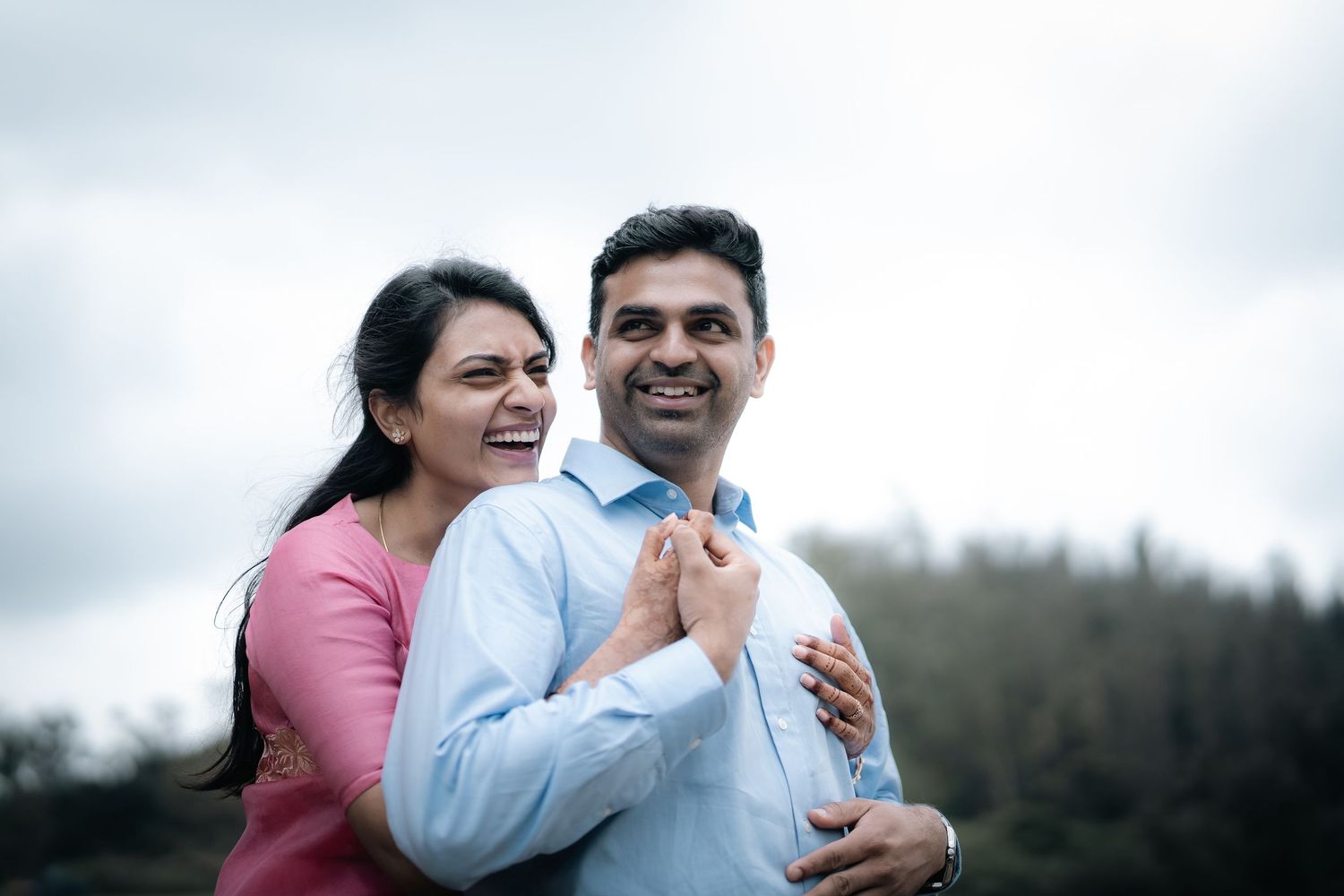 Happy couple sharing a tender moment against a cloudy sky.