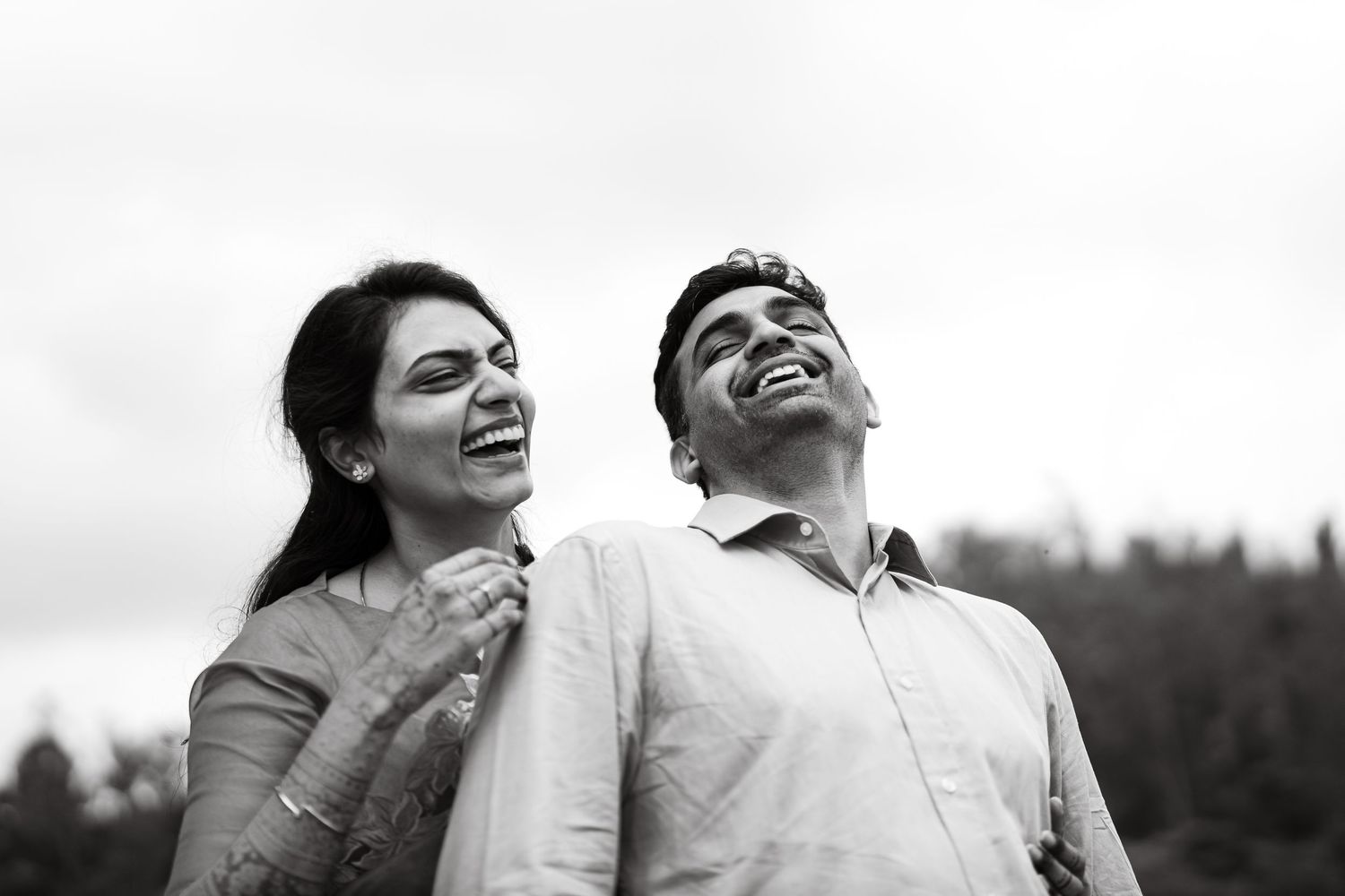 A couple shares a joyful moment together while laughing outdoors.