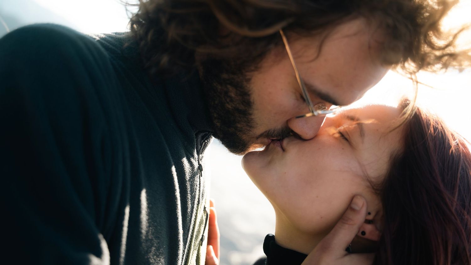 Two people share an intimate kiss in a series of romantic close-up shots against a dark background.