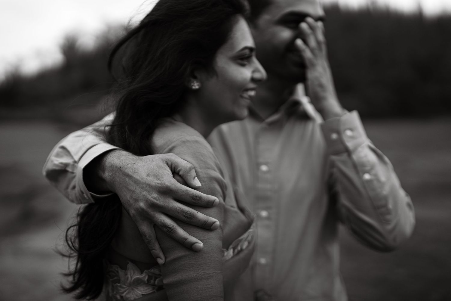 Black and white portrait of a couple sharing an intimate moment outdoors.