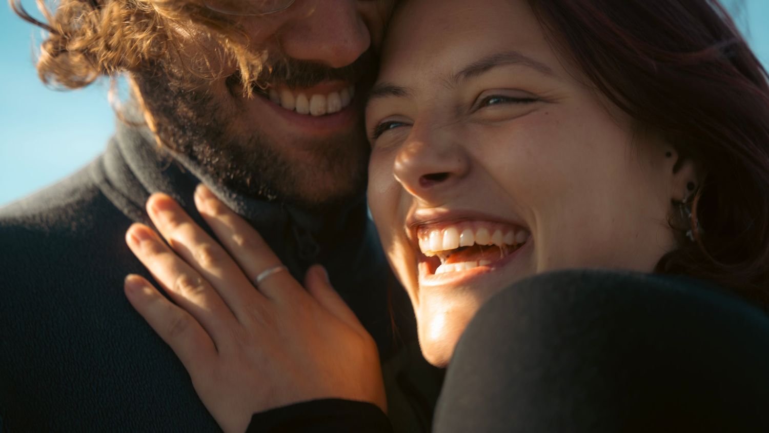 A couple sharing a joyful intimate moment together in warm sunlight.