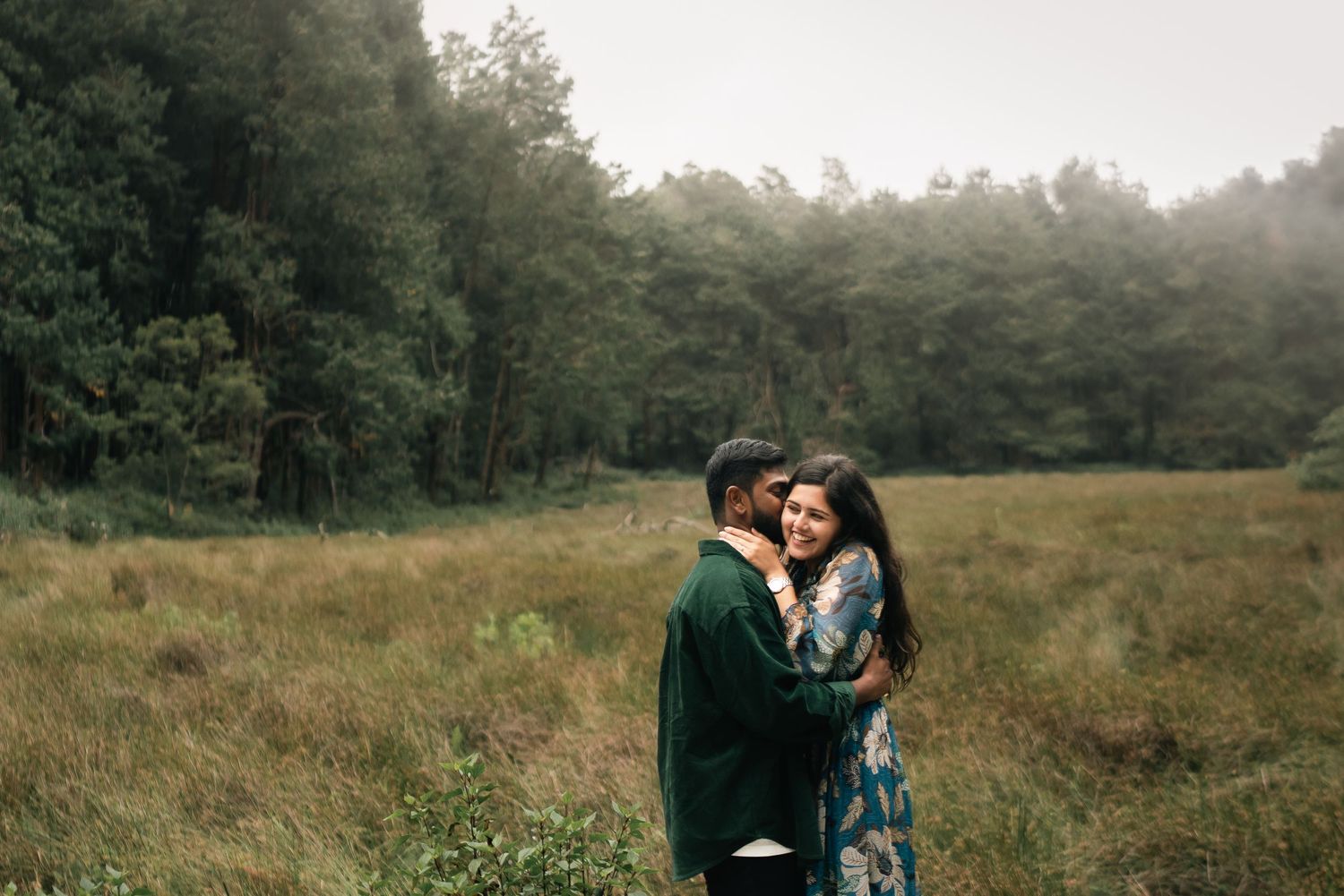 Couple exploring a misty forest trail together wearing casual outfits.