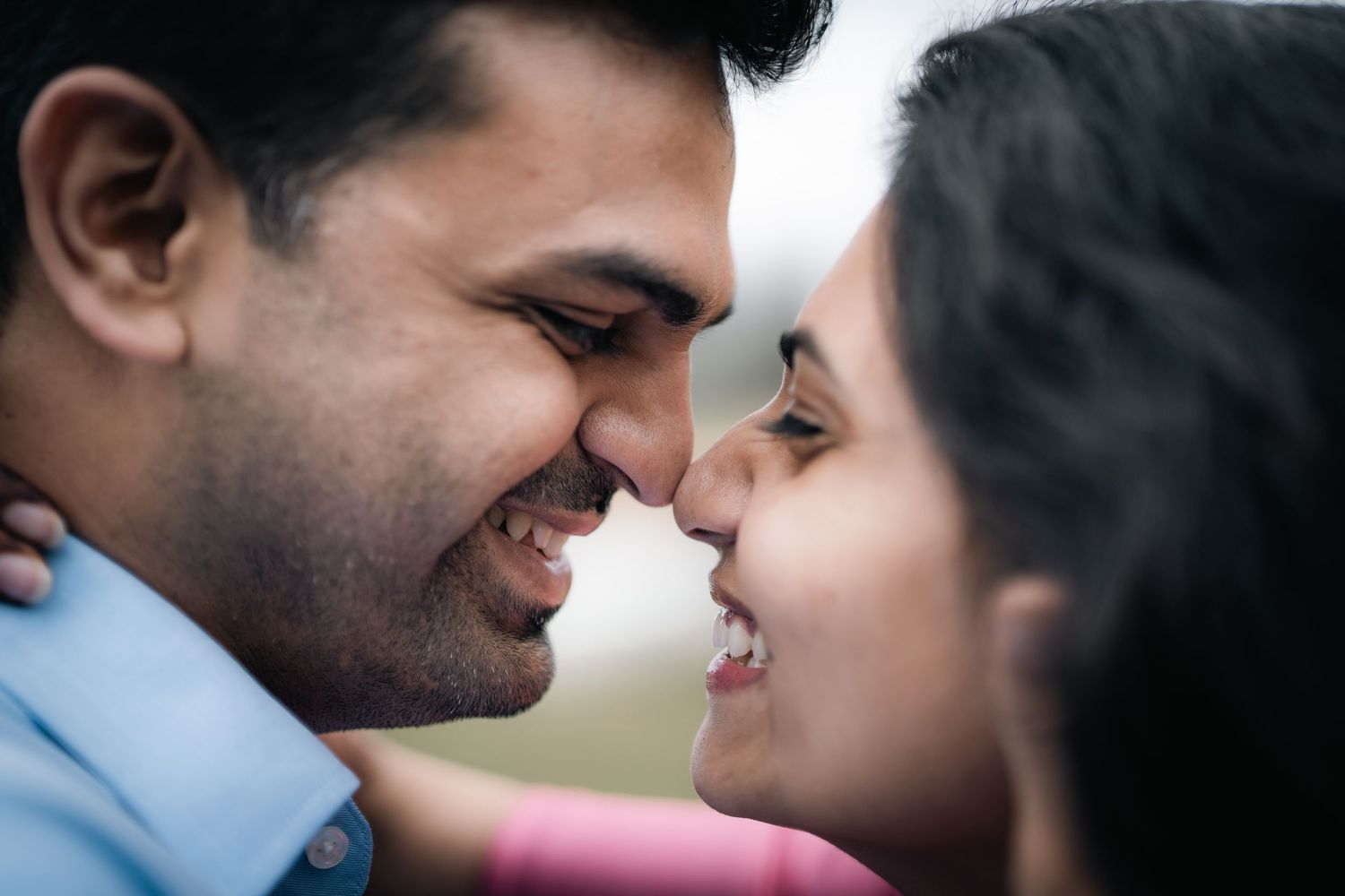 A romantic close-up shot of a couple sharing an intimate moment while smiling at each other.