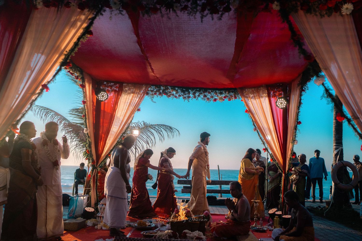 Outdoor wedding venue with red and white draped canopy against a scenic backdrop.