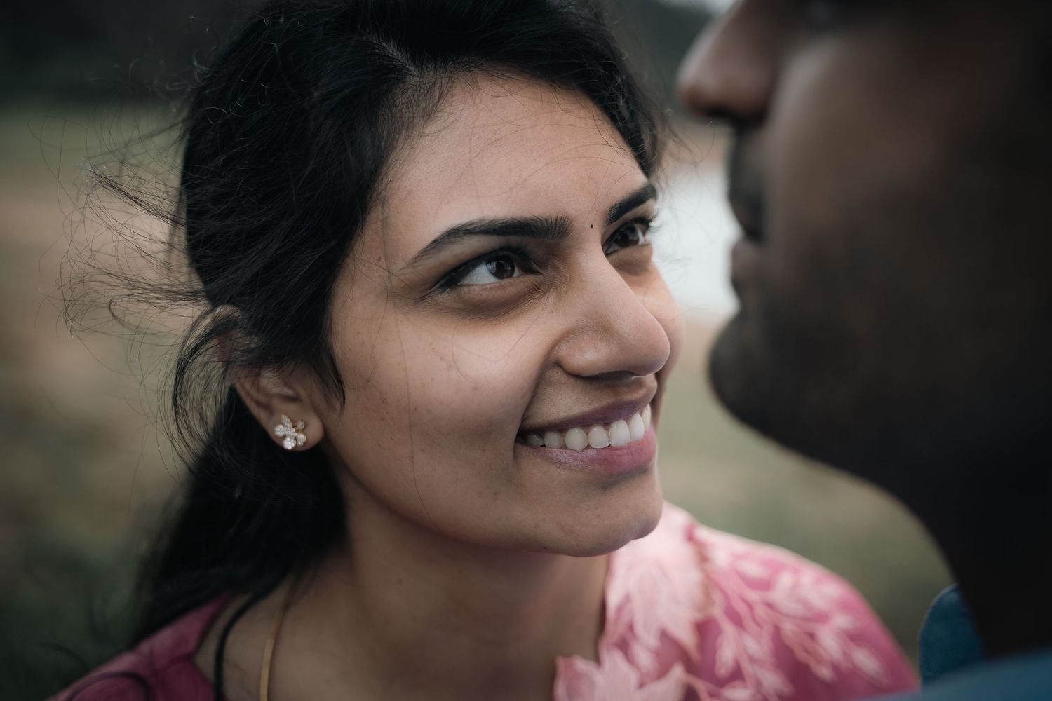 Couple sharing joyful smiles in a candid outdoor portrait.