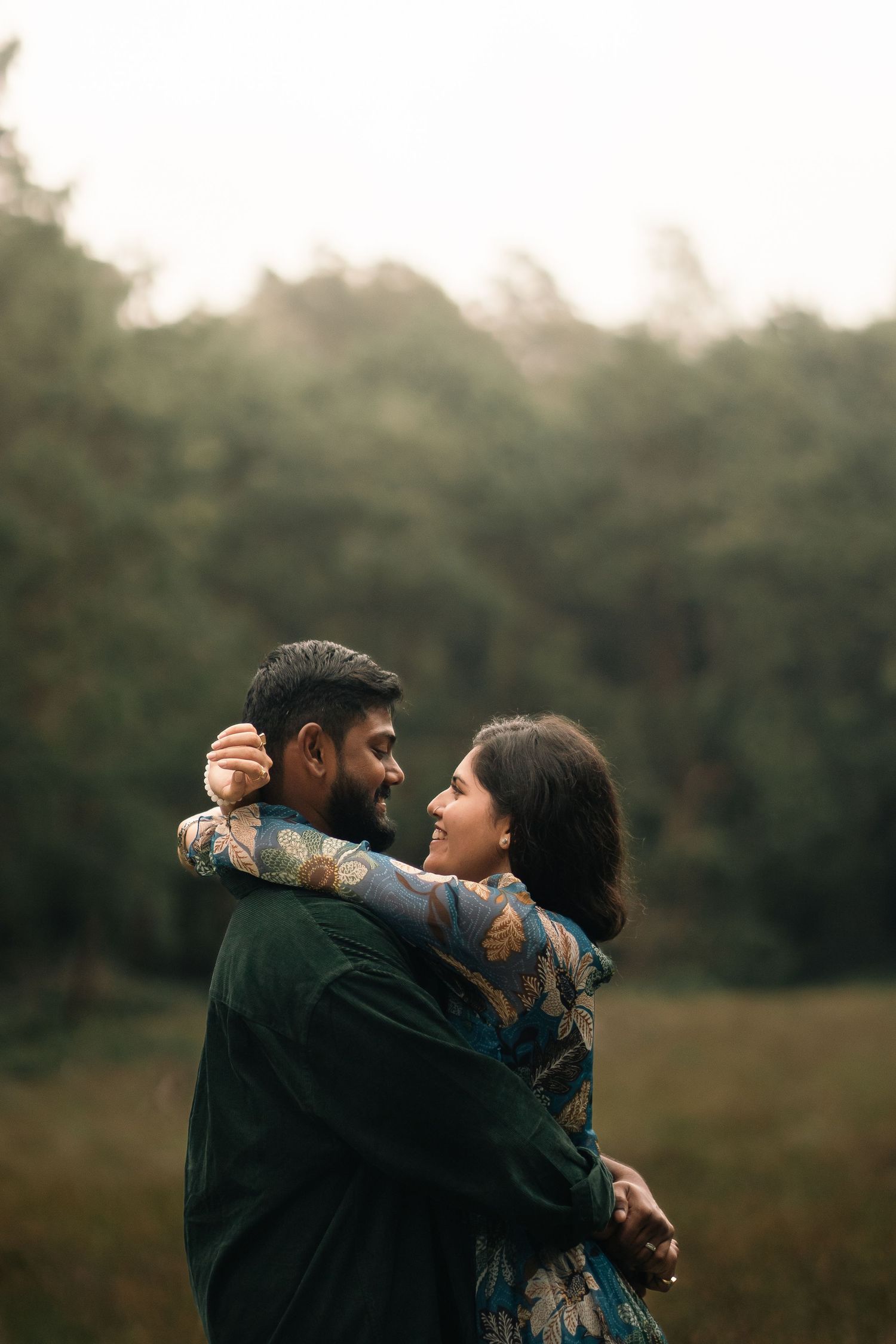 Romantic couple embracing in a misty natural setting during golden hour.