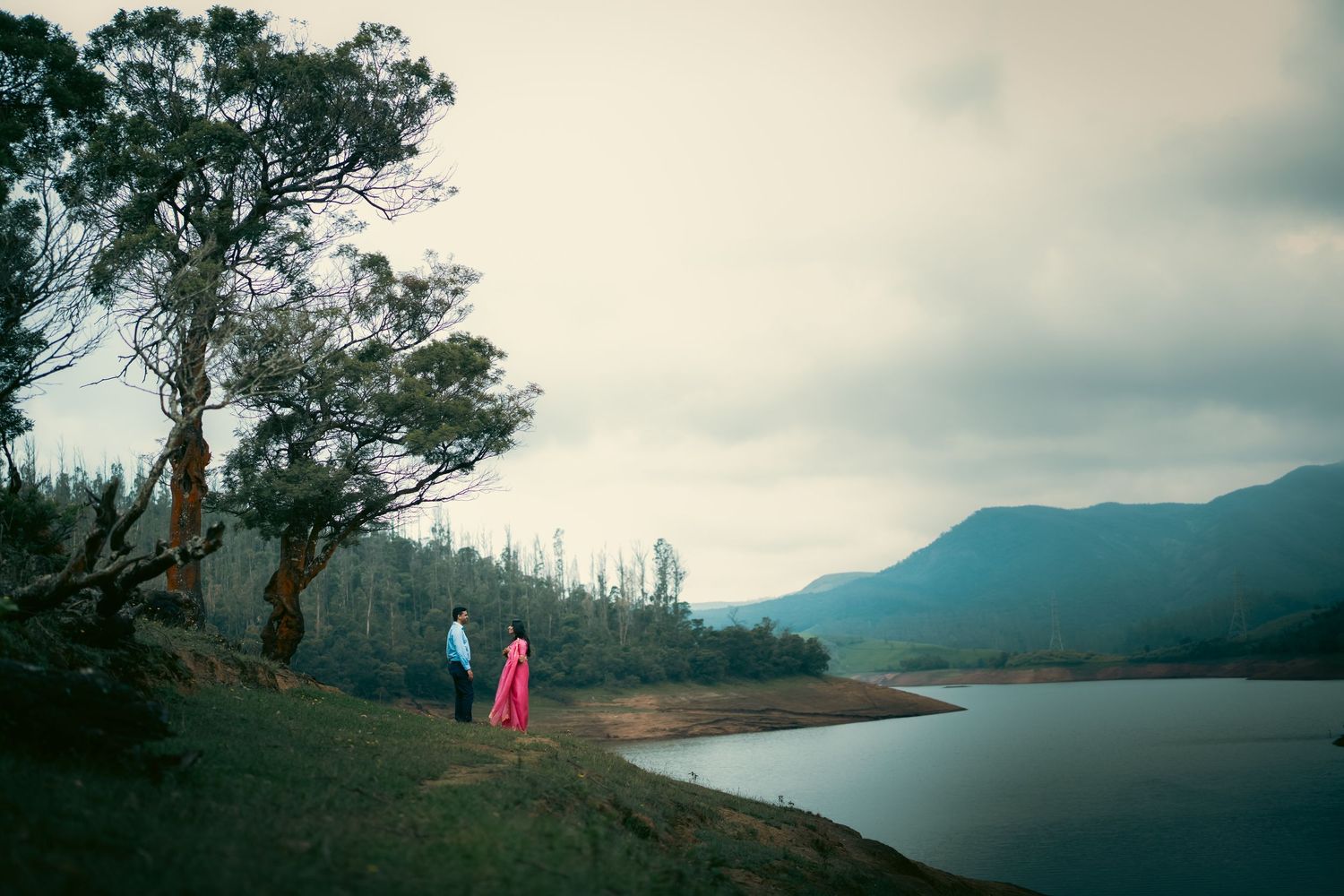 Panoramic landscape view of a lake surrounded by mountains and trees.