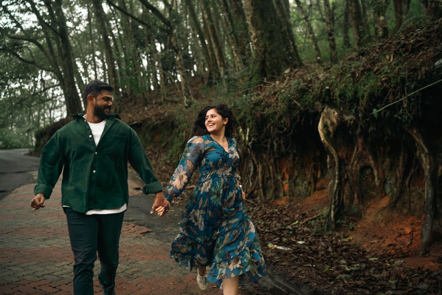 Couple strolling along a scenic wooded pathway surrounded by trees.