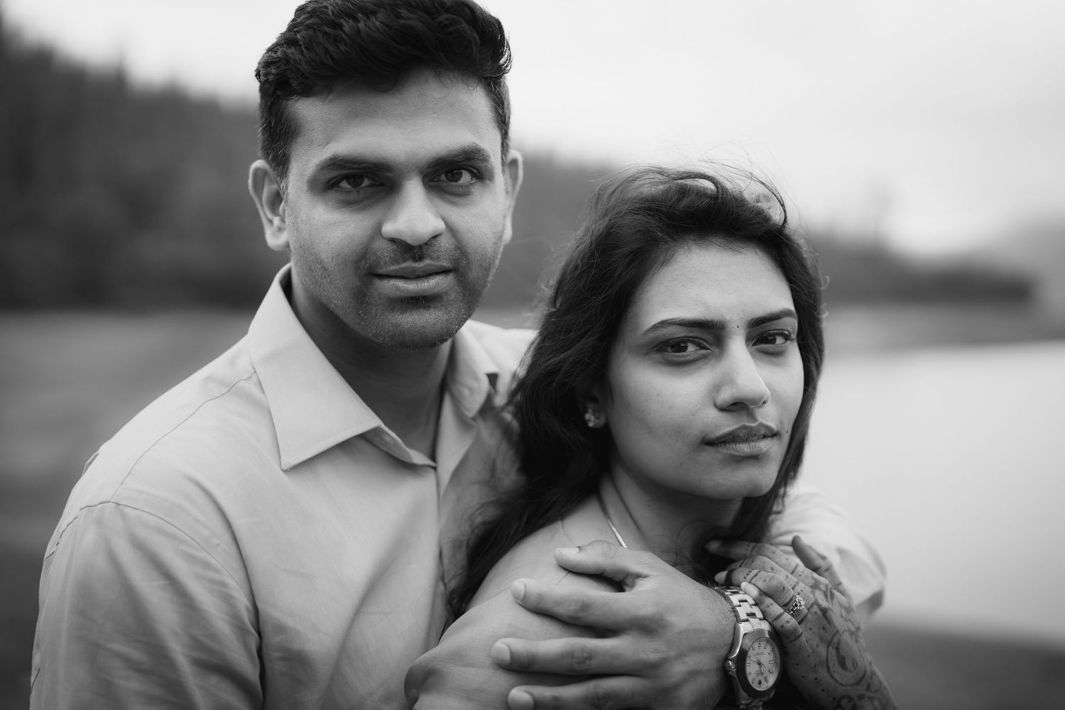 Black and white portrait of couple sharing intimate moment by lake.