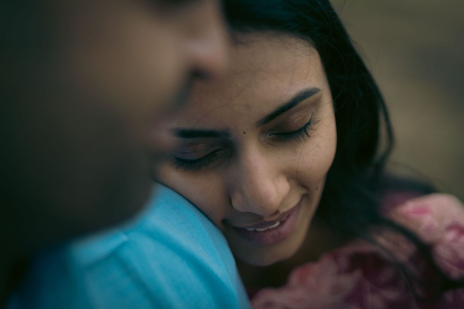 Atmospheric close-up portrait of a couple in soft lighting.