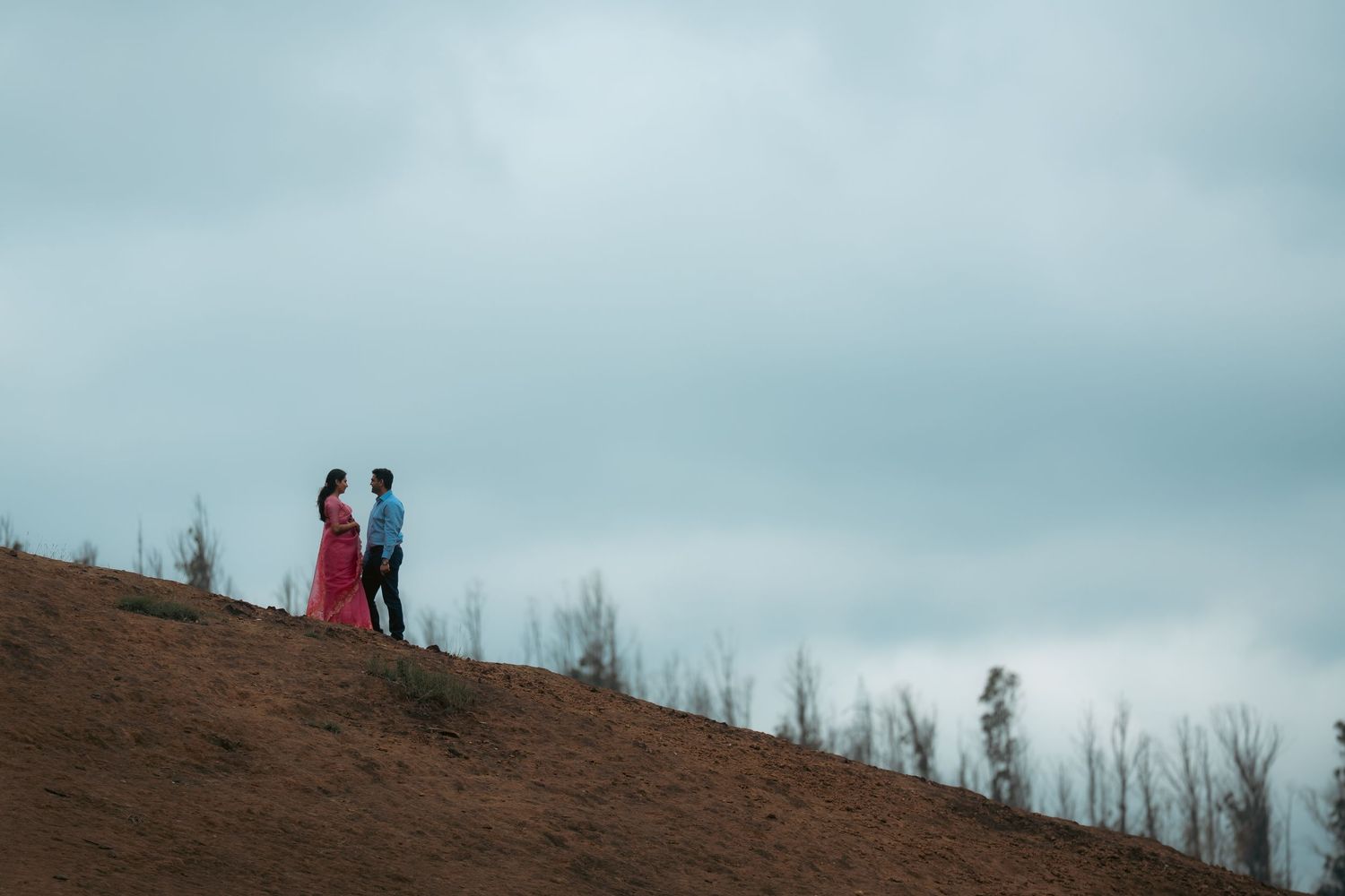 Scenic hilltop photoshoot with mountain lake and cloudy sky in the background.