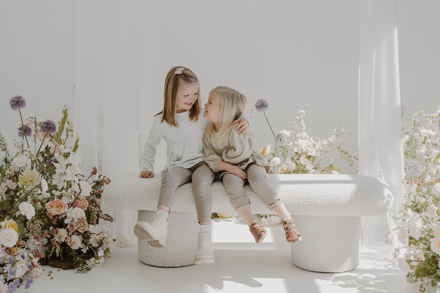Artistic display of white ceramic pottery and spring flowers in a bright, airy studio setting.