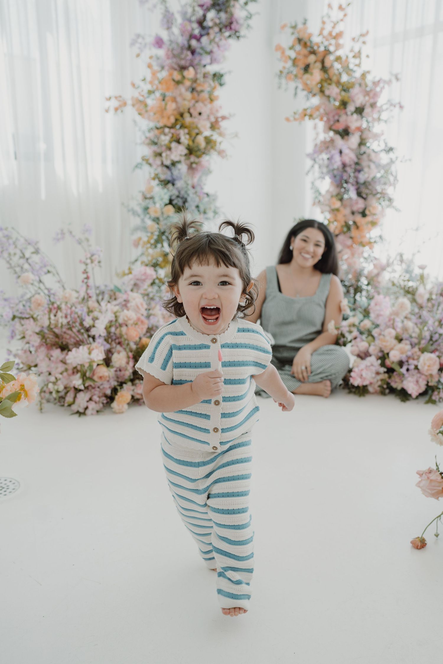 Candid studio photoshoot featuring striped outfit and floral decorations.