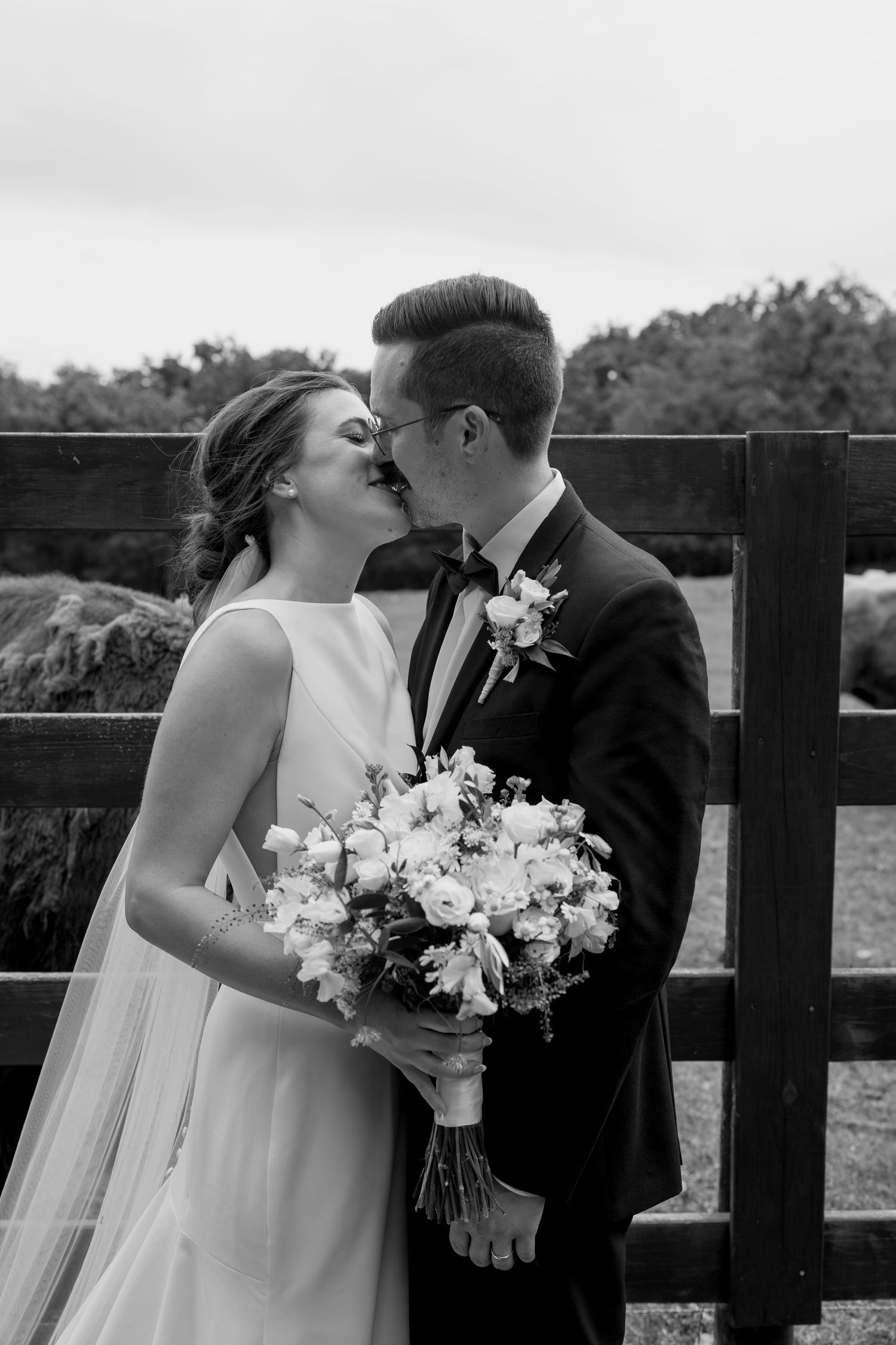 Intimate wedding portraits showing tender moments between couple by rustic farm fence.