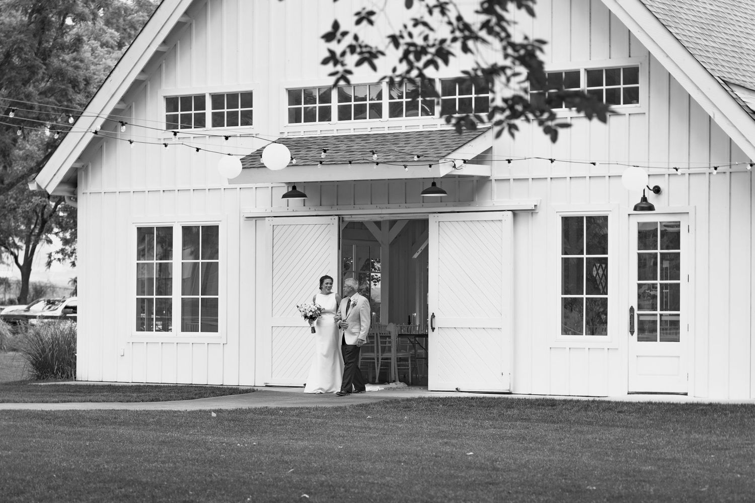 Exterior view of a modern white wedding venue with large windows and barn-style architecture.