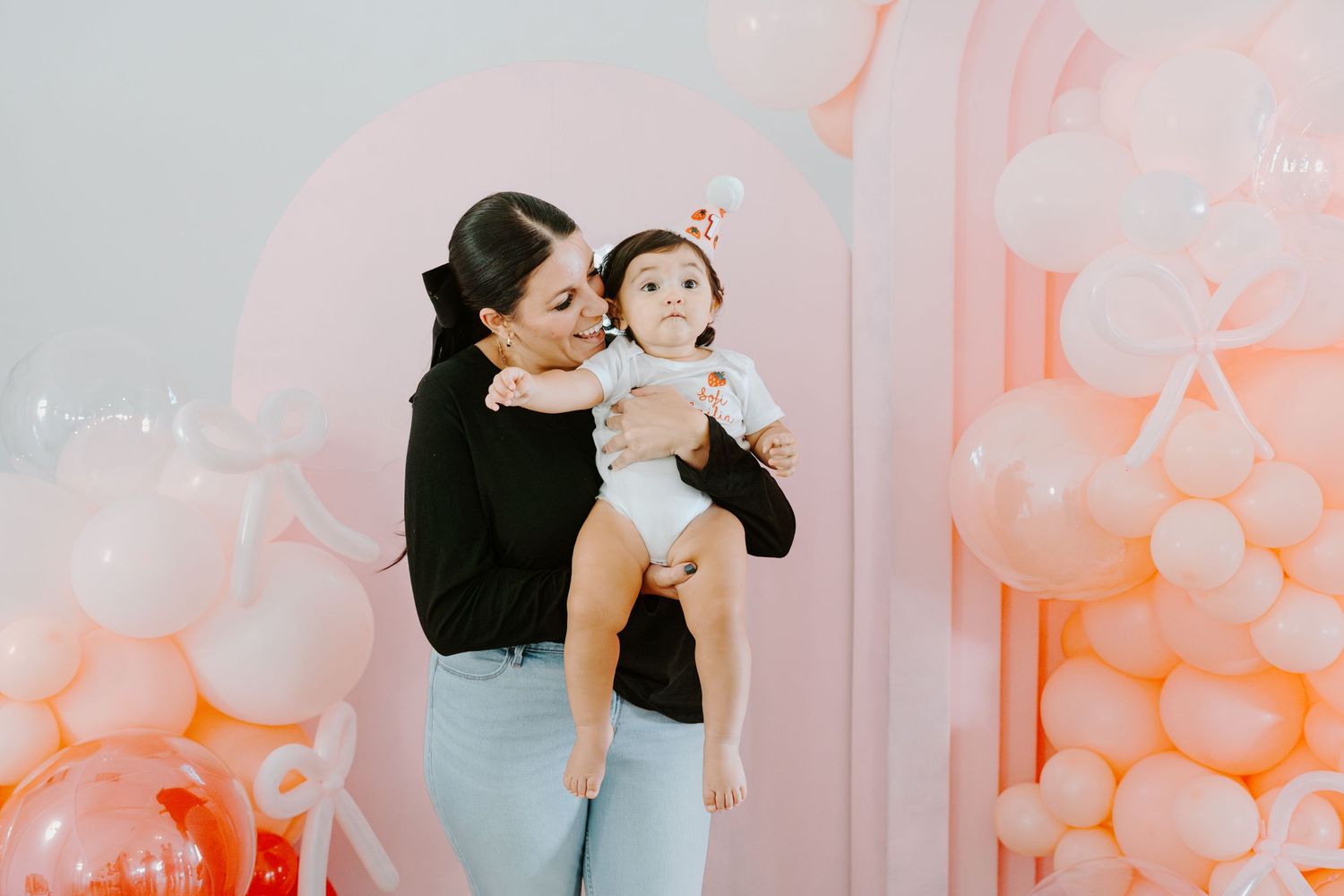 A festive scene with peach and coral balloons decorating a bright white interior space.