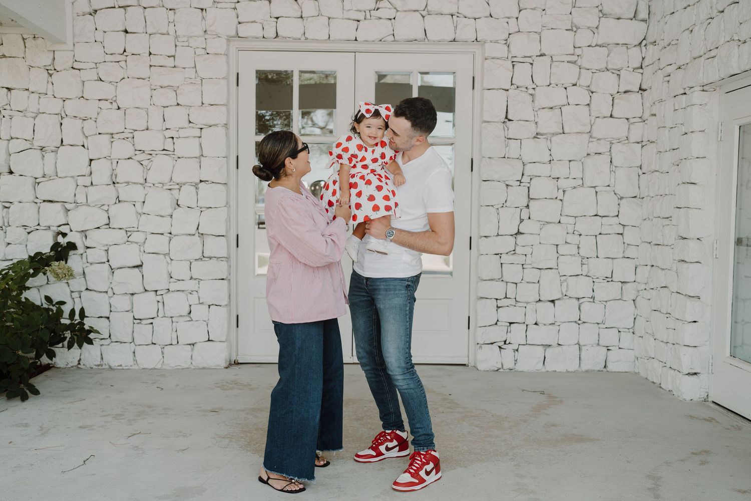 A heartwarming family moment captured against a white brick wall background.