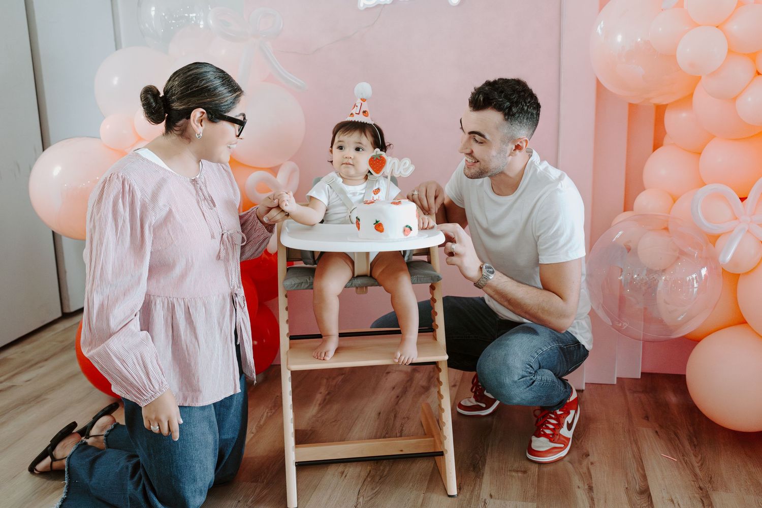 Birthday photoshoot setup with pink balloons and neon happy birthday sign.