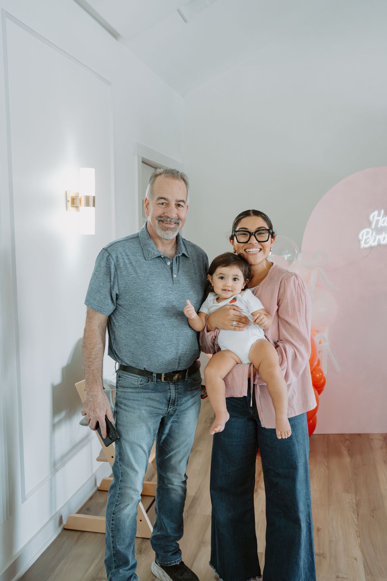 Multi-generational family gathering in a modern studio with pink balloon accents.