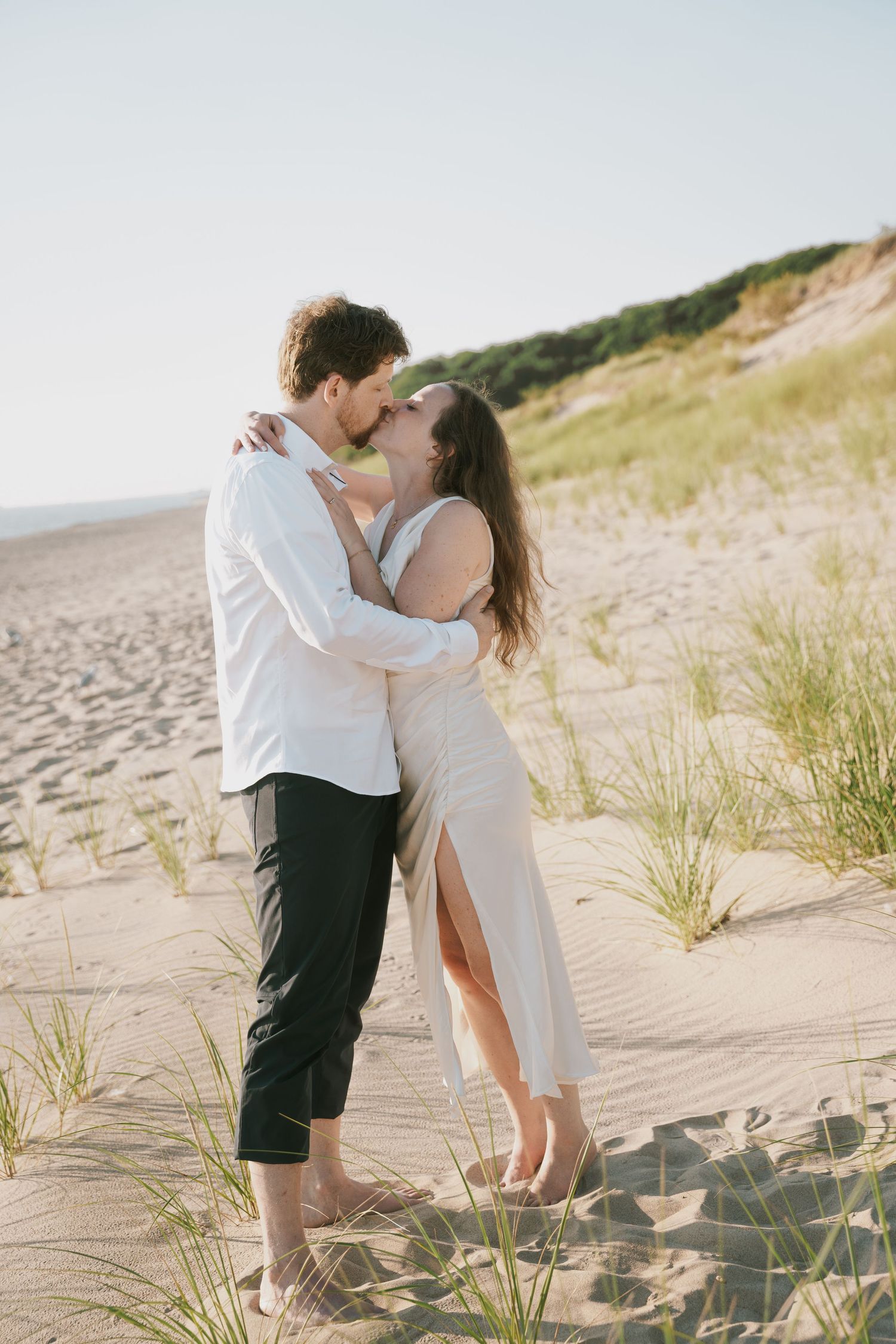 A romantic beach photoshoot featuring a couple among coastal dunes.