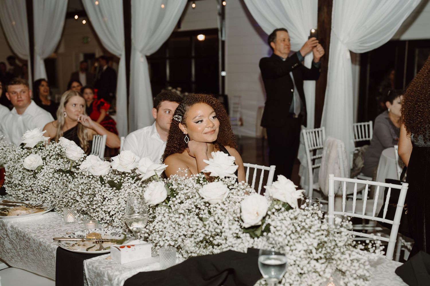 Reception tables decorated with white floral arrangements and elegant place settings.