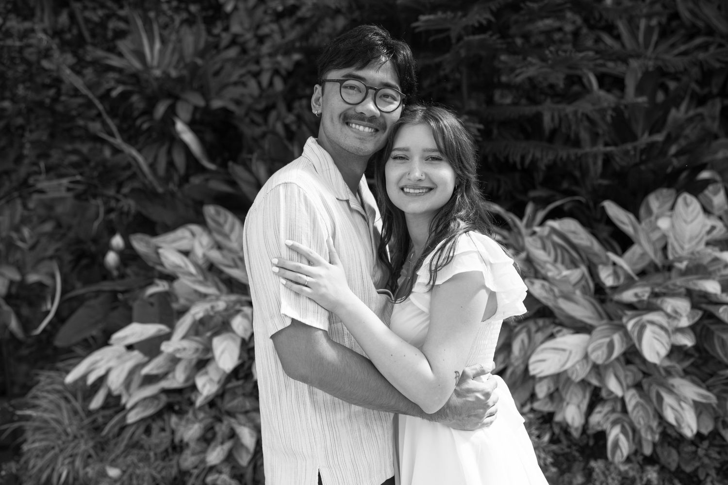 Black and white photograph of a romantic moment in a botanical garden setting.