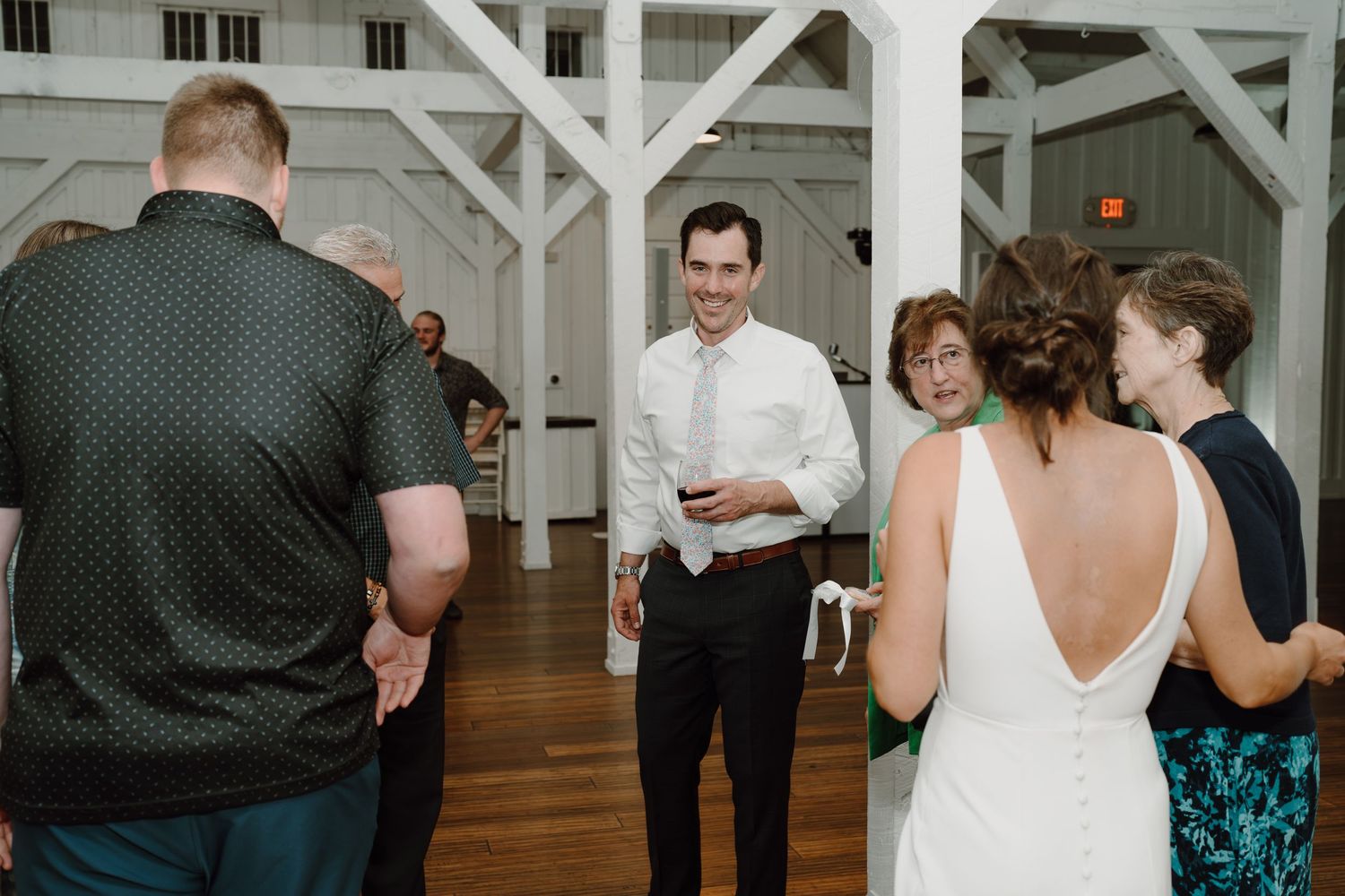 Wedding reception in a bright white venue with exposed beams and hardwood floors.