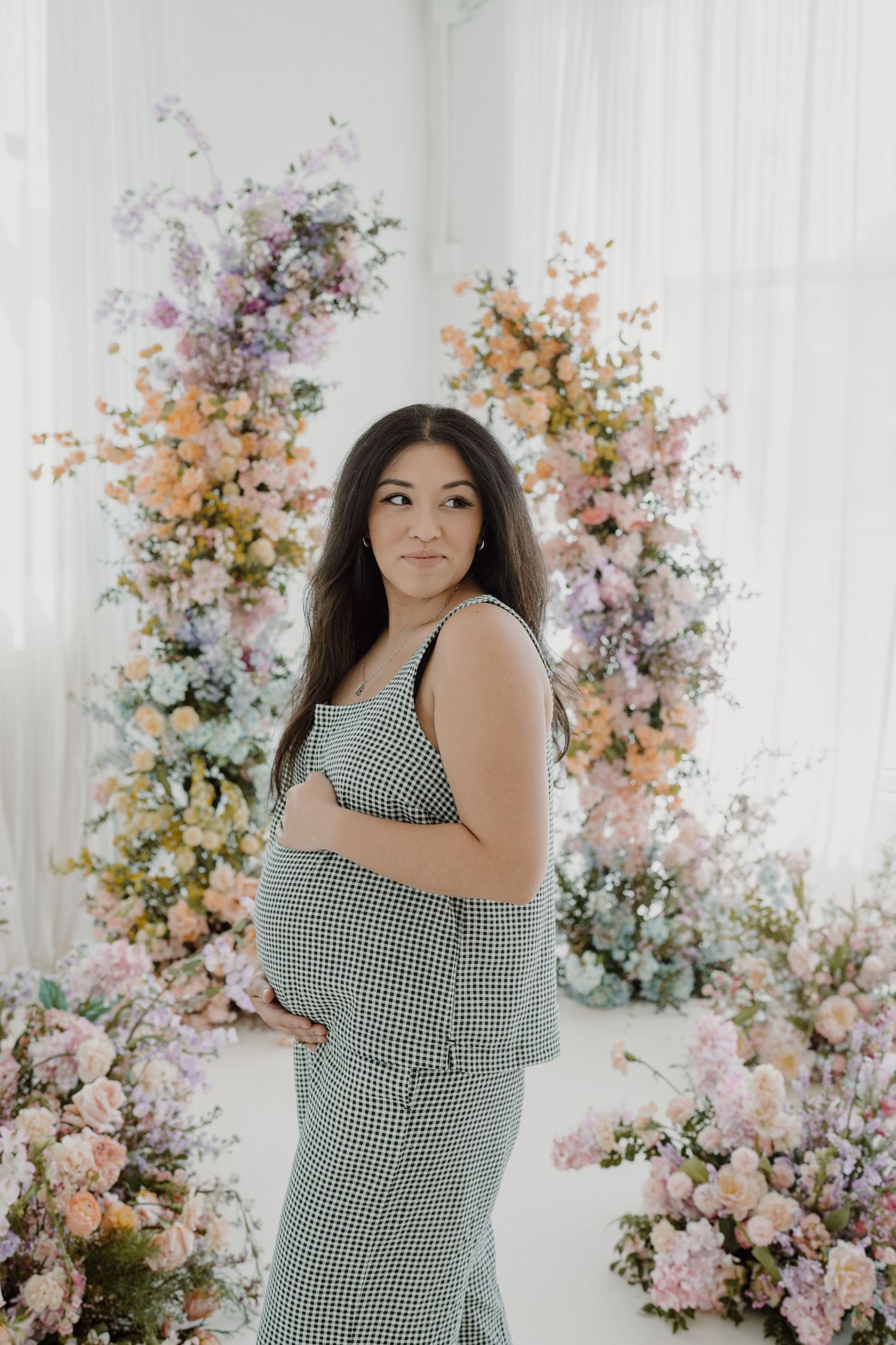 Beautiful maternity portraits with gingham dress against romantic floral backdrops.