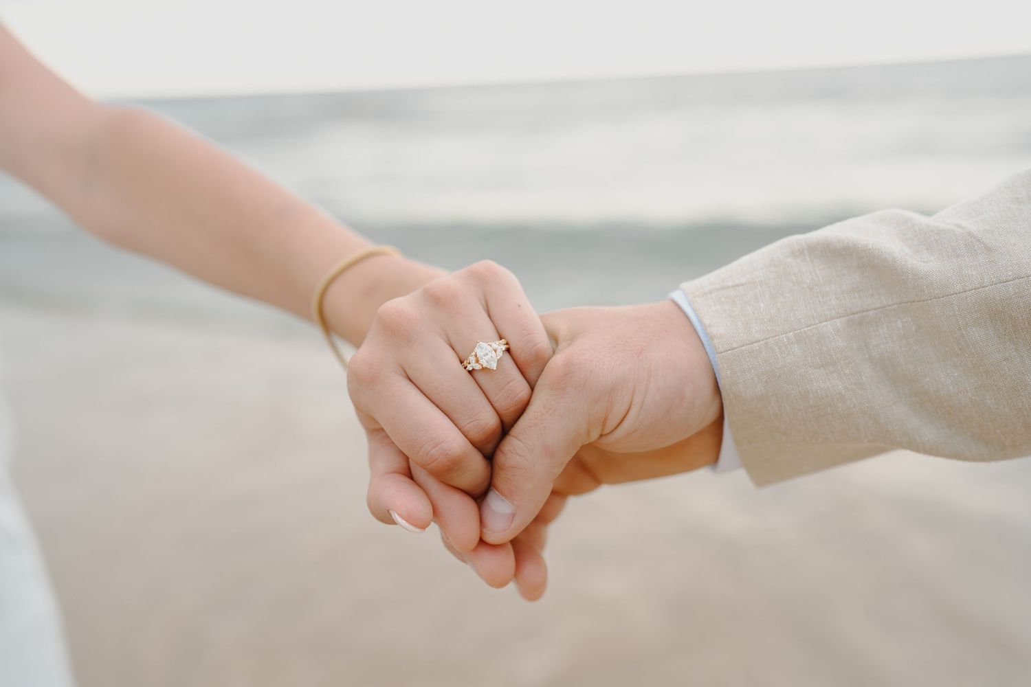 Close-up of hands holding each other with an engagement ring visible.