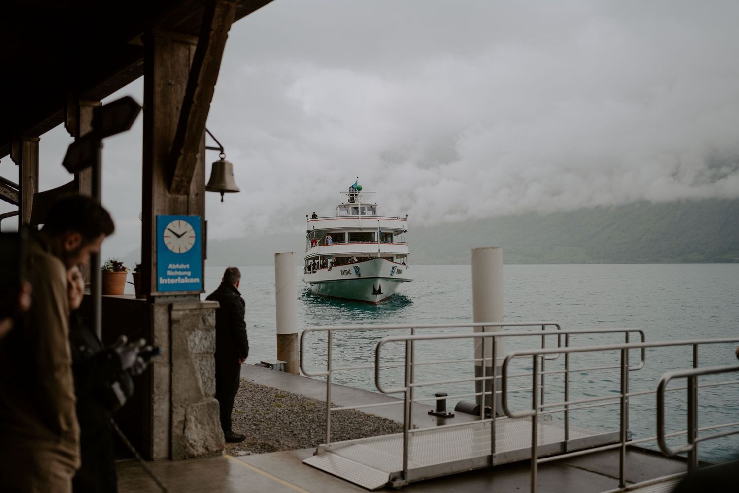 Dock with metal railings overlooking a foggy lake with boats in the distance.
