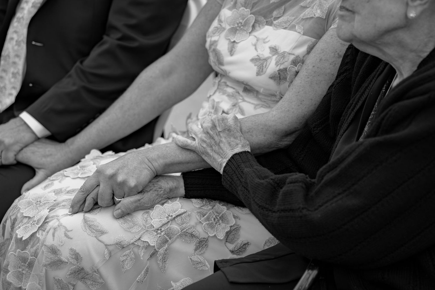 Wedding guests seated in formal attire during an outdoor ceremony.