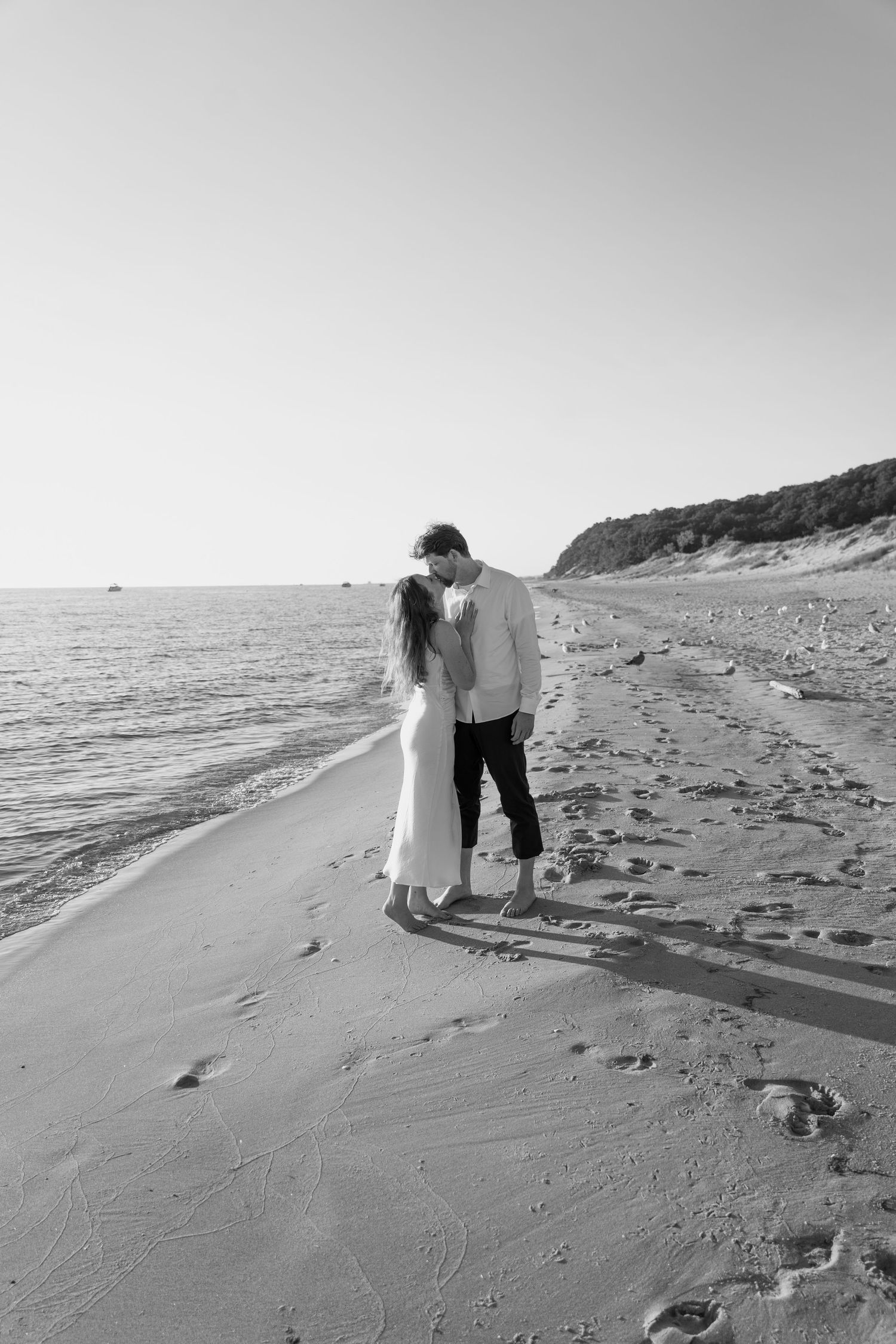 A black and white beach scene with a couple silhouetted against the ocean.