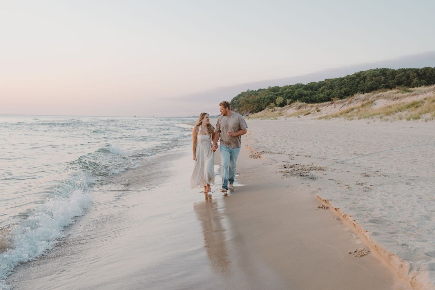 Couple enjoying a peaceful walk by the ocean with coastal cliffs in the background.