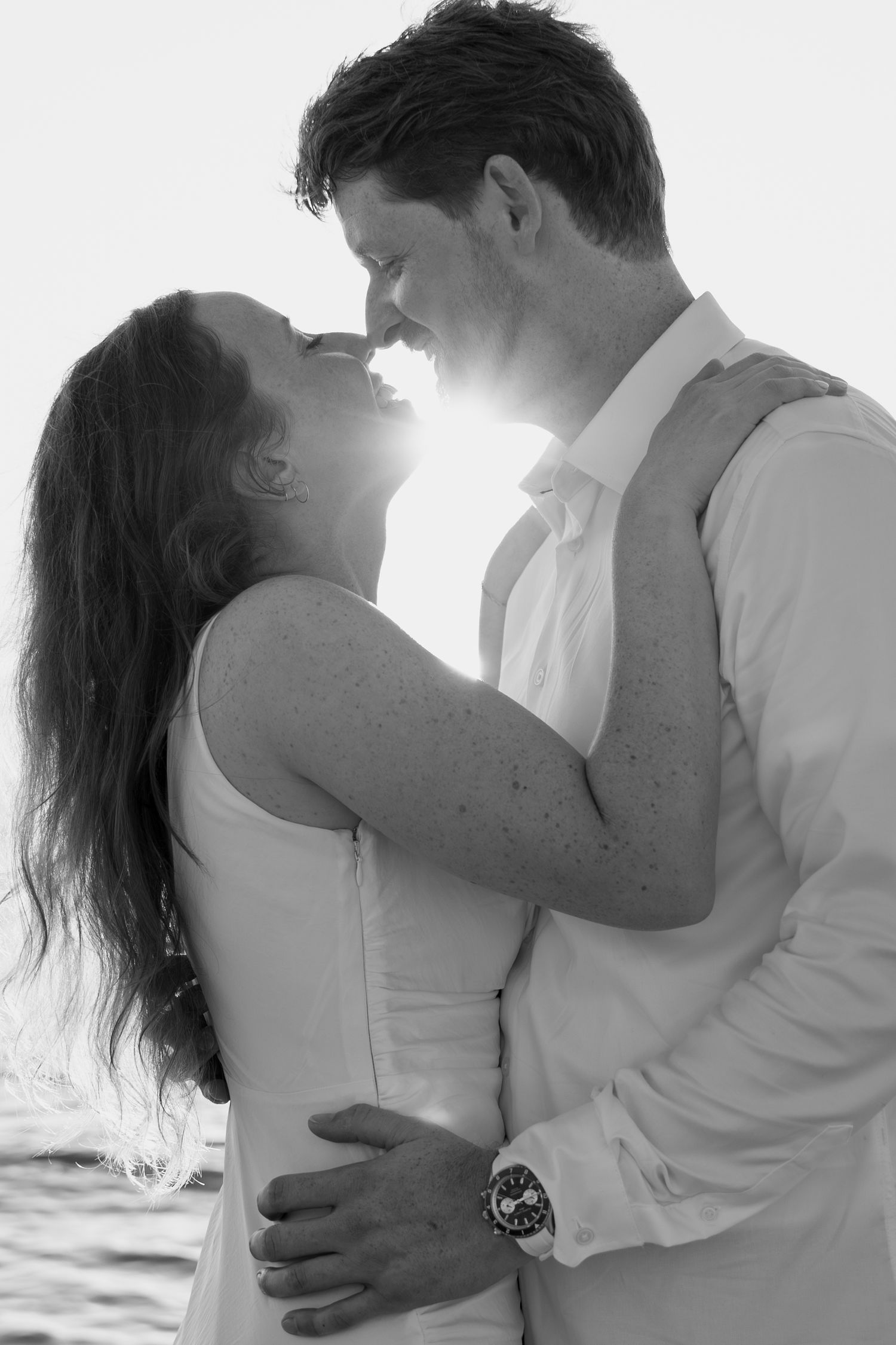 Black and white portrait of couple in romantic pose by the ocean.