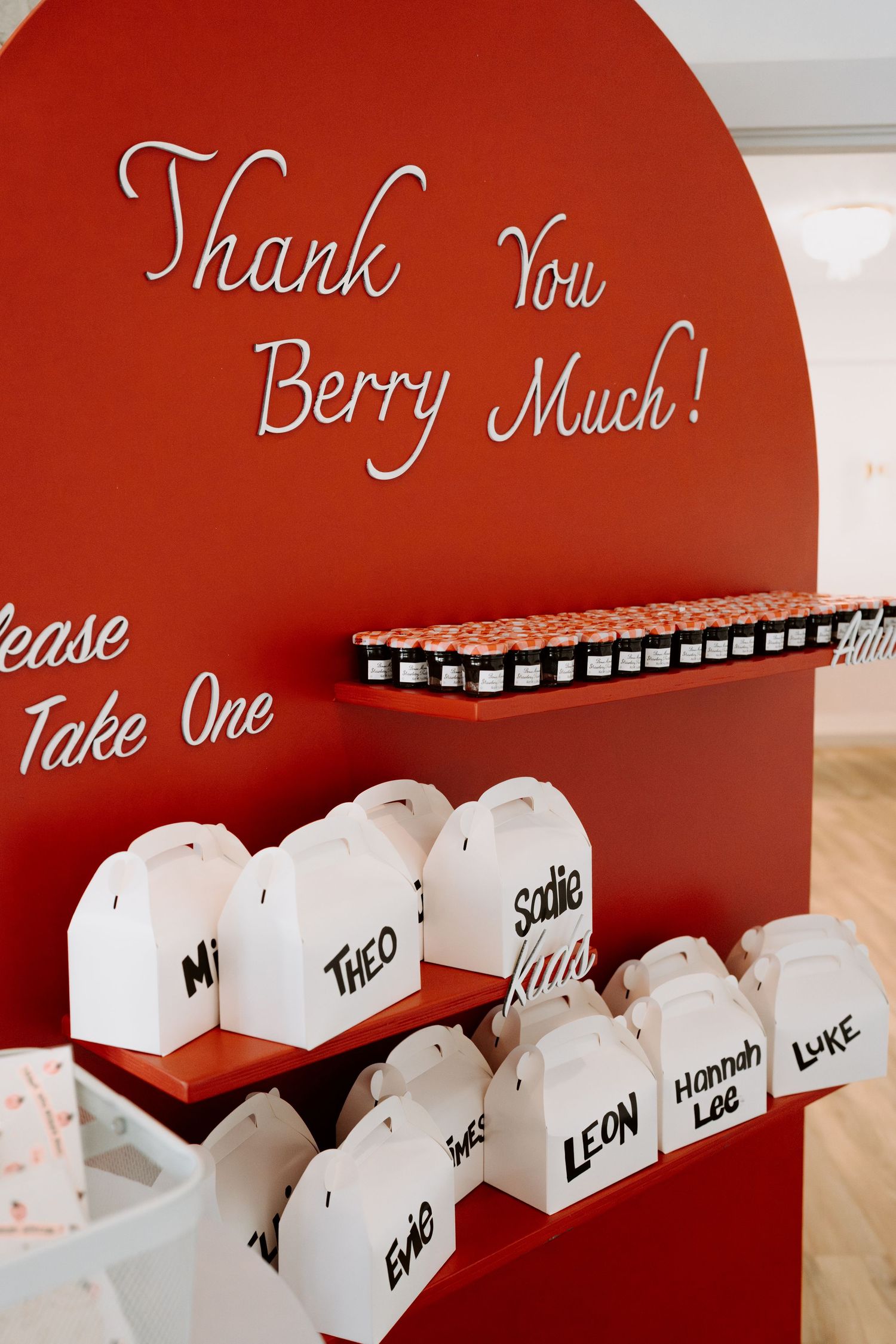 Red arched wall display with 'Thank You Berry Much' text and white gift boxes.