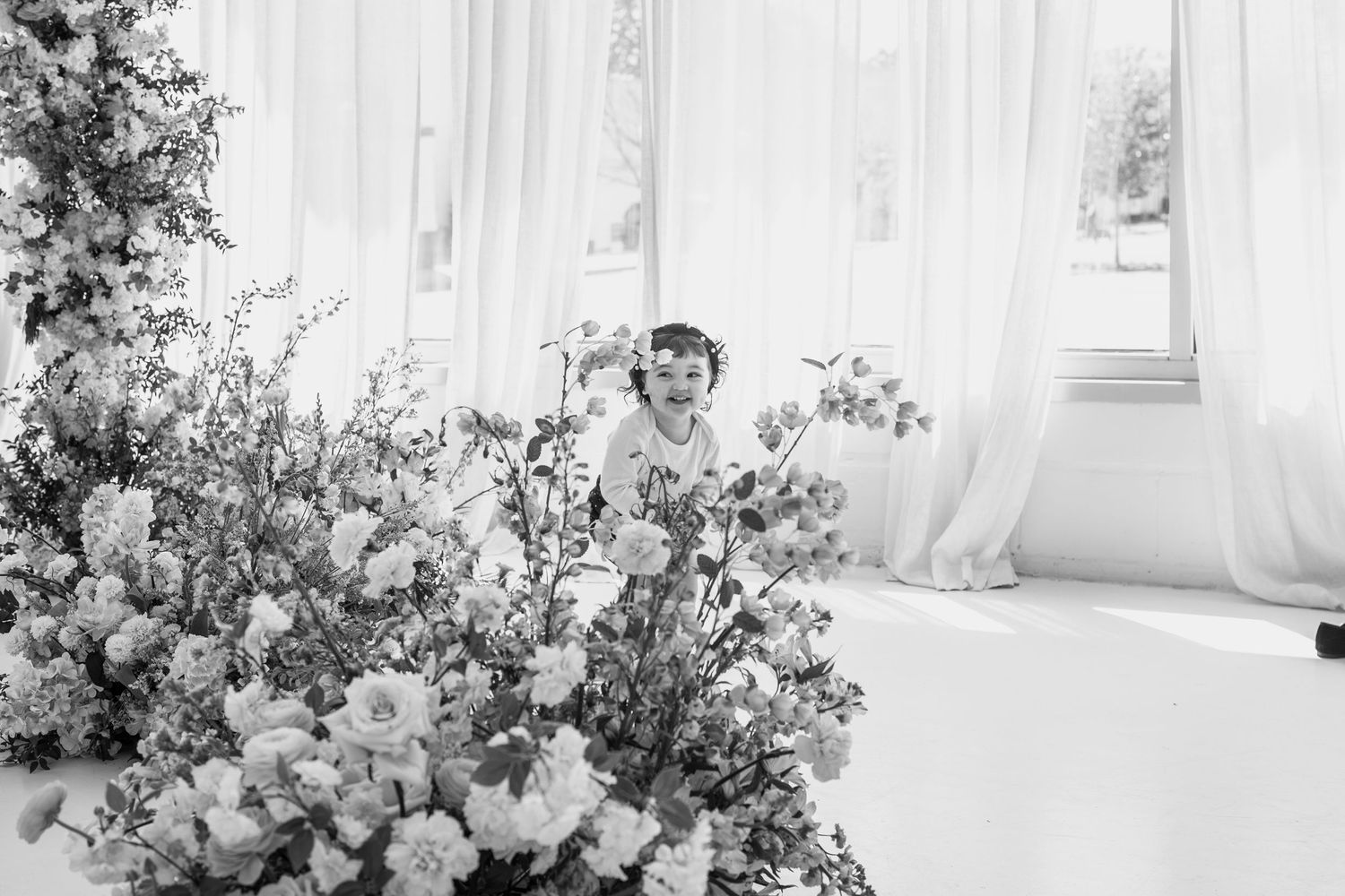 Elegant floral arrangements frame a bright white photography studio space.