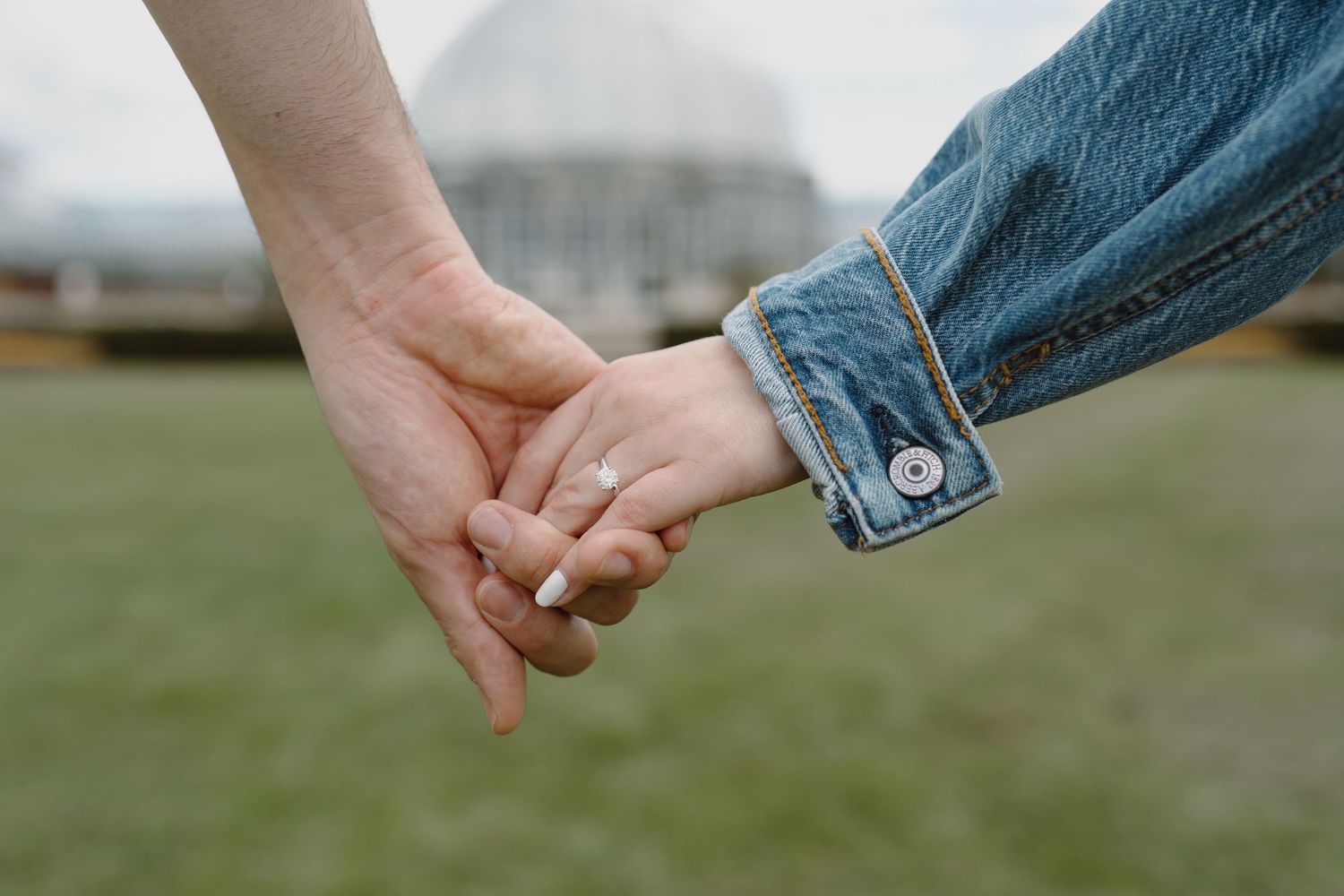 Close-up of hands reaching and connecting with denim sleeves visible.