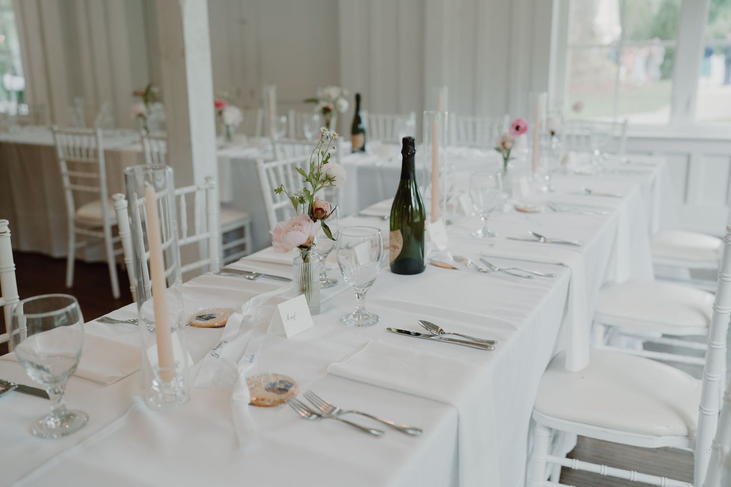 Minimalist wedding reception setup with white tablecloths and chiavari chairs.