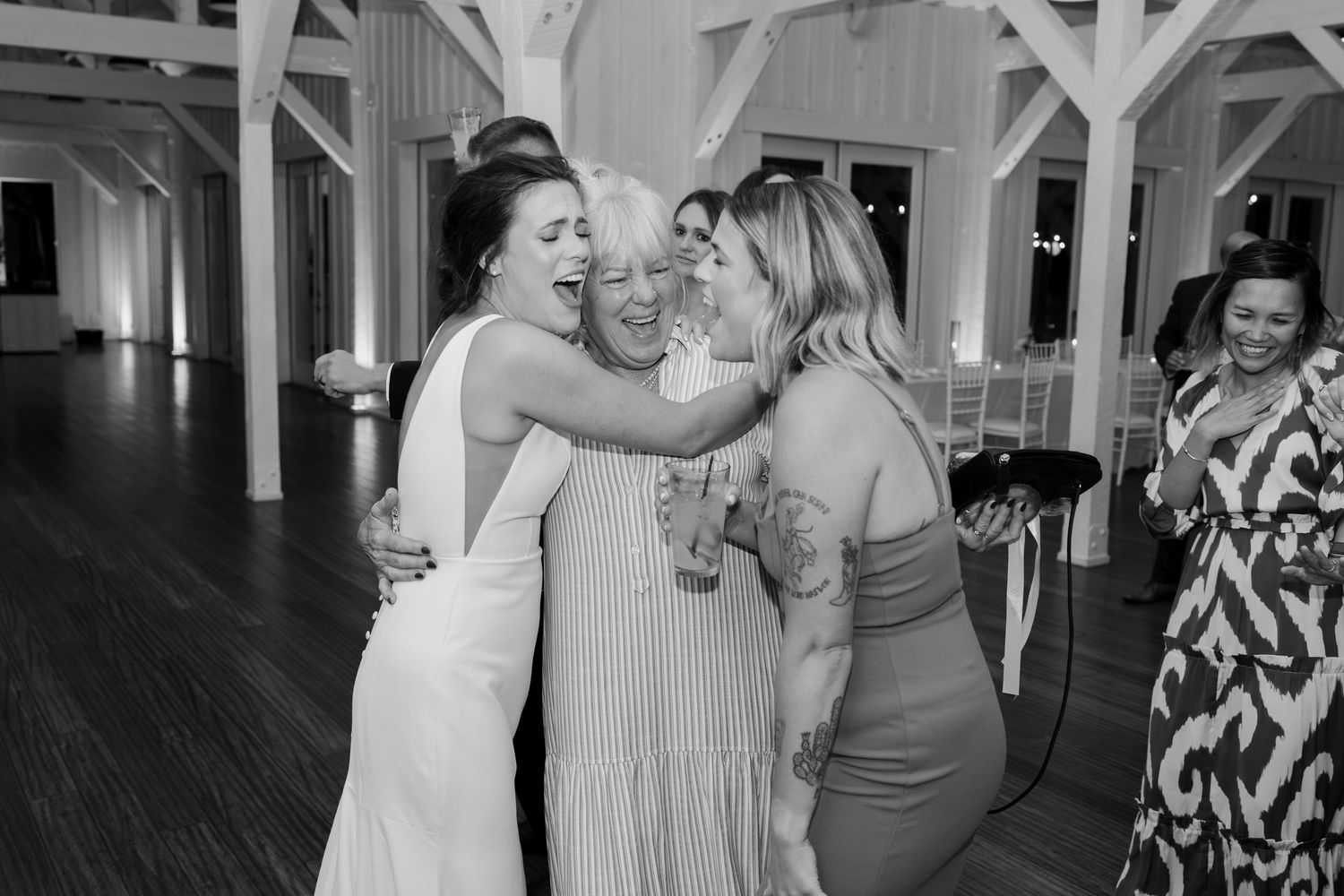 Wedding guests share a joyful moment dancing together at an elegant indoor reception venue.