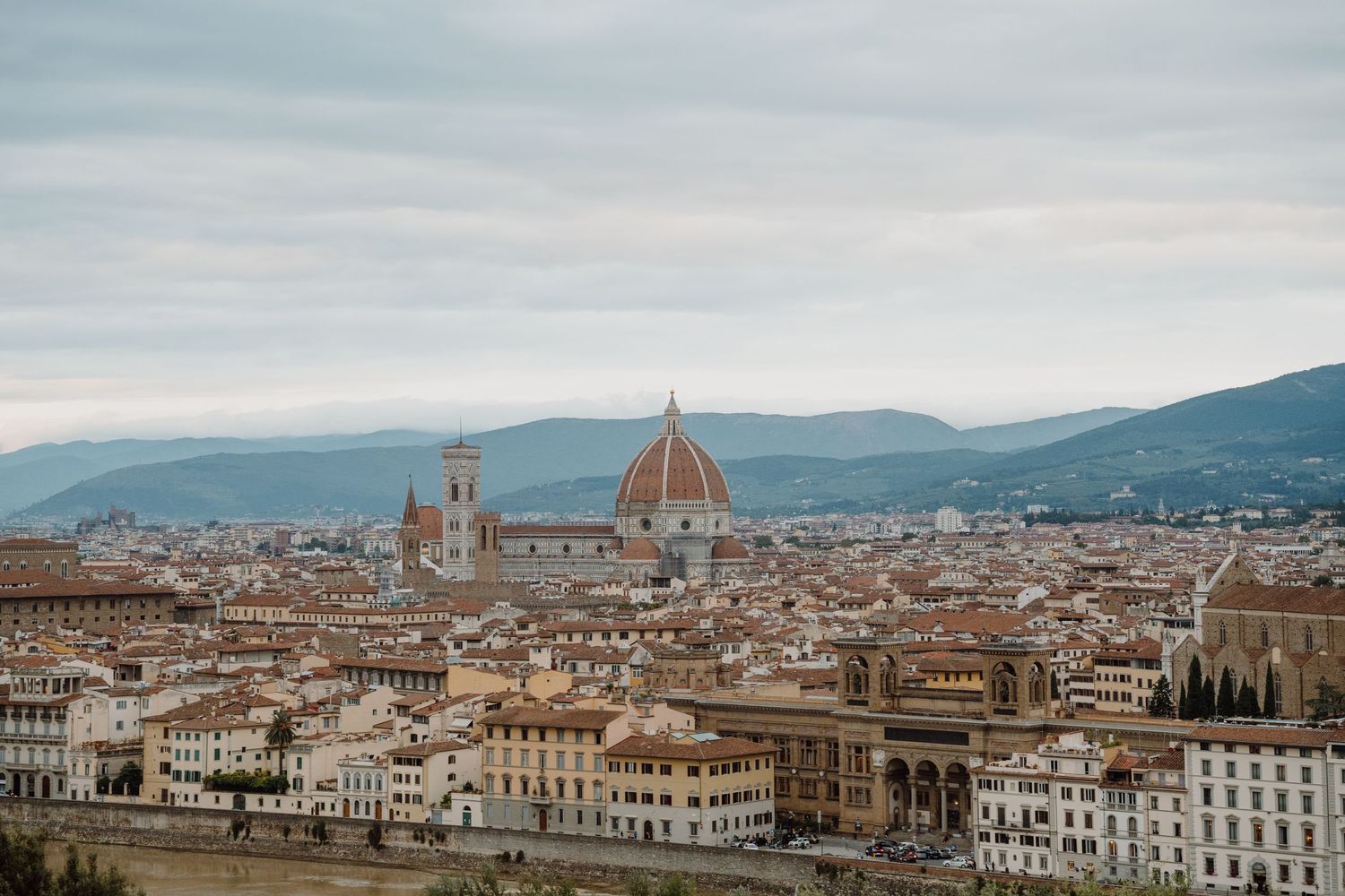 Panoramic cityscape of Florence, Italy featuring the iconic Duomo cathedral and historic buildings.