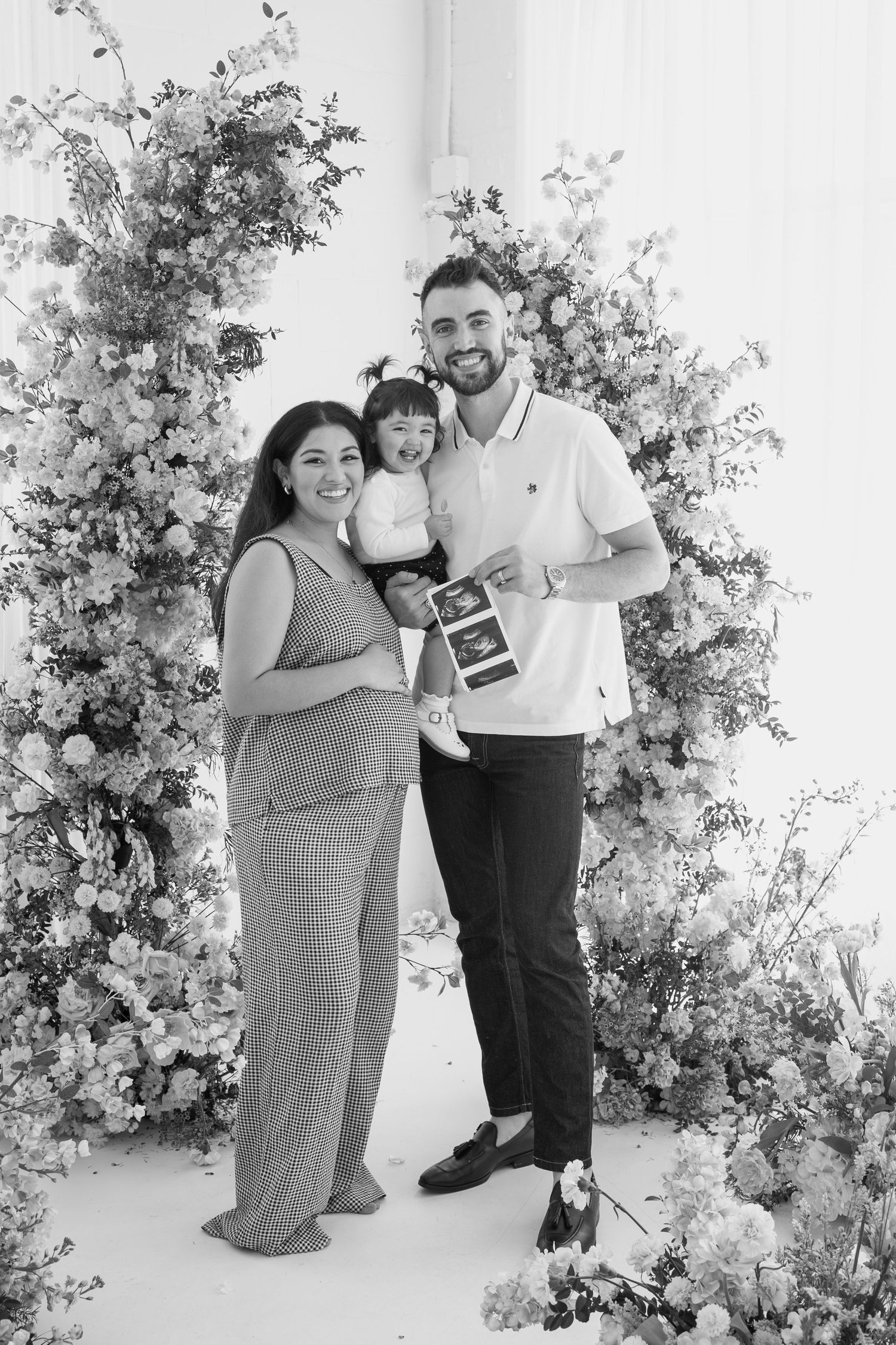 Black and white photo of a family sharing their pregnancy news with ultrasound images.