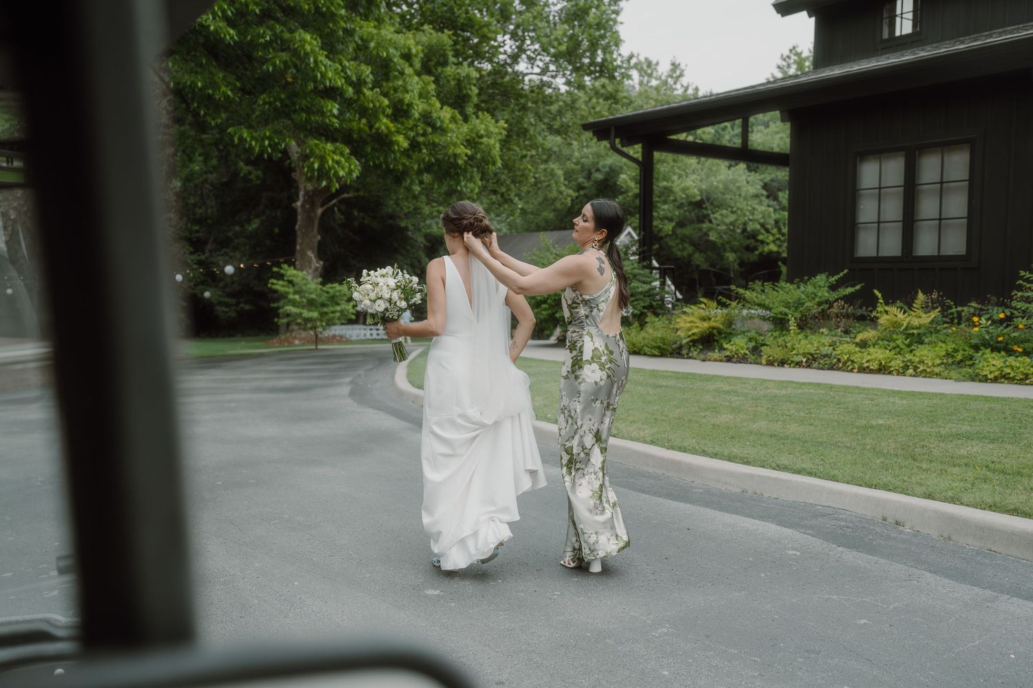 People walking on an outdoor pathway viewed through a vehicle window.