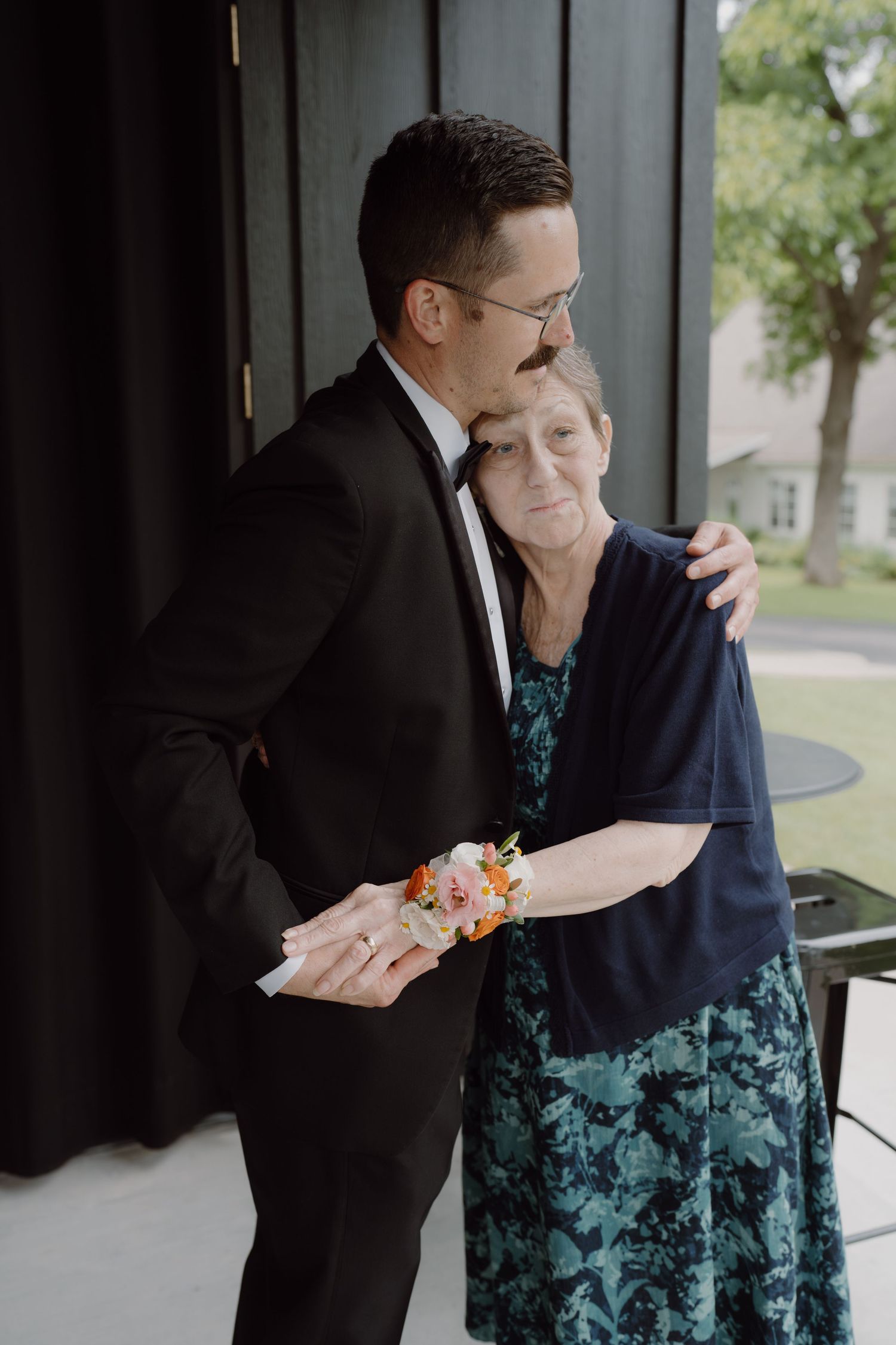 Wedding party members share laughs while helping with formal attire preparations.