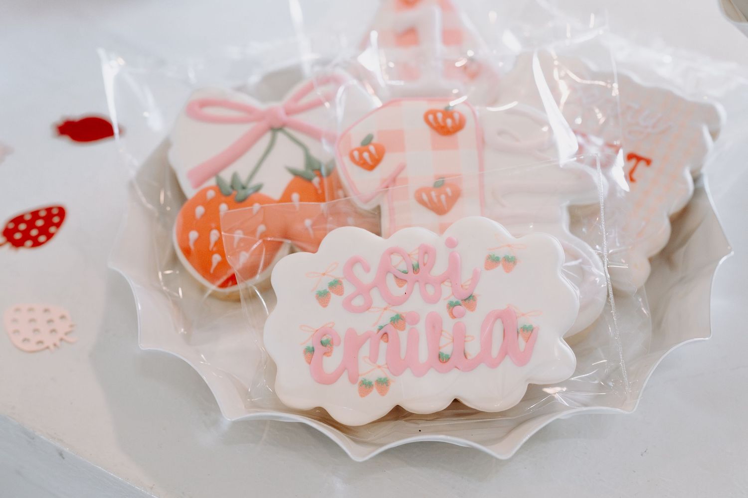 Translucent party favor bags with pink strawberry decorations laid out in a row.