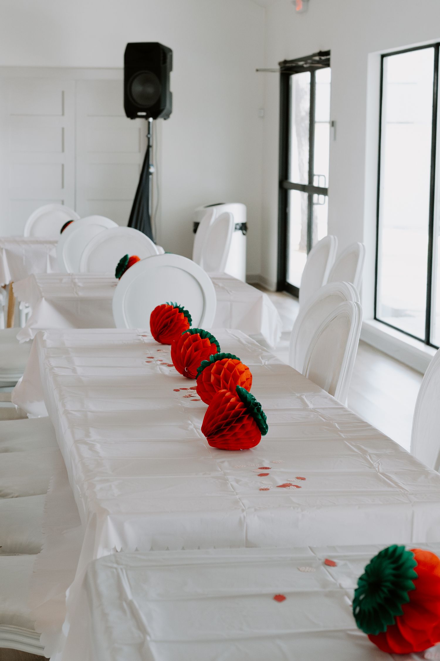 White event space with red and black paper pom pom decorations on tables.