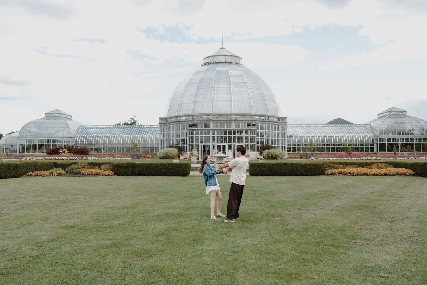Panoramic shot of a domed greenhouse structure with visitors on the surrounding green grounds.