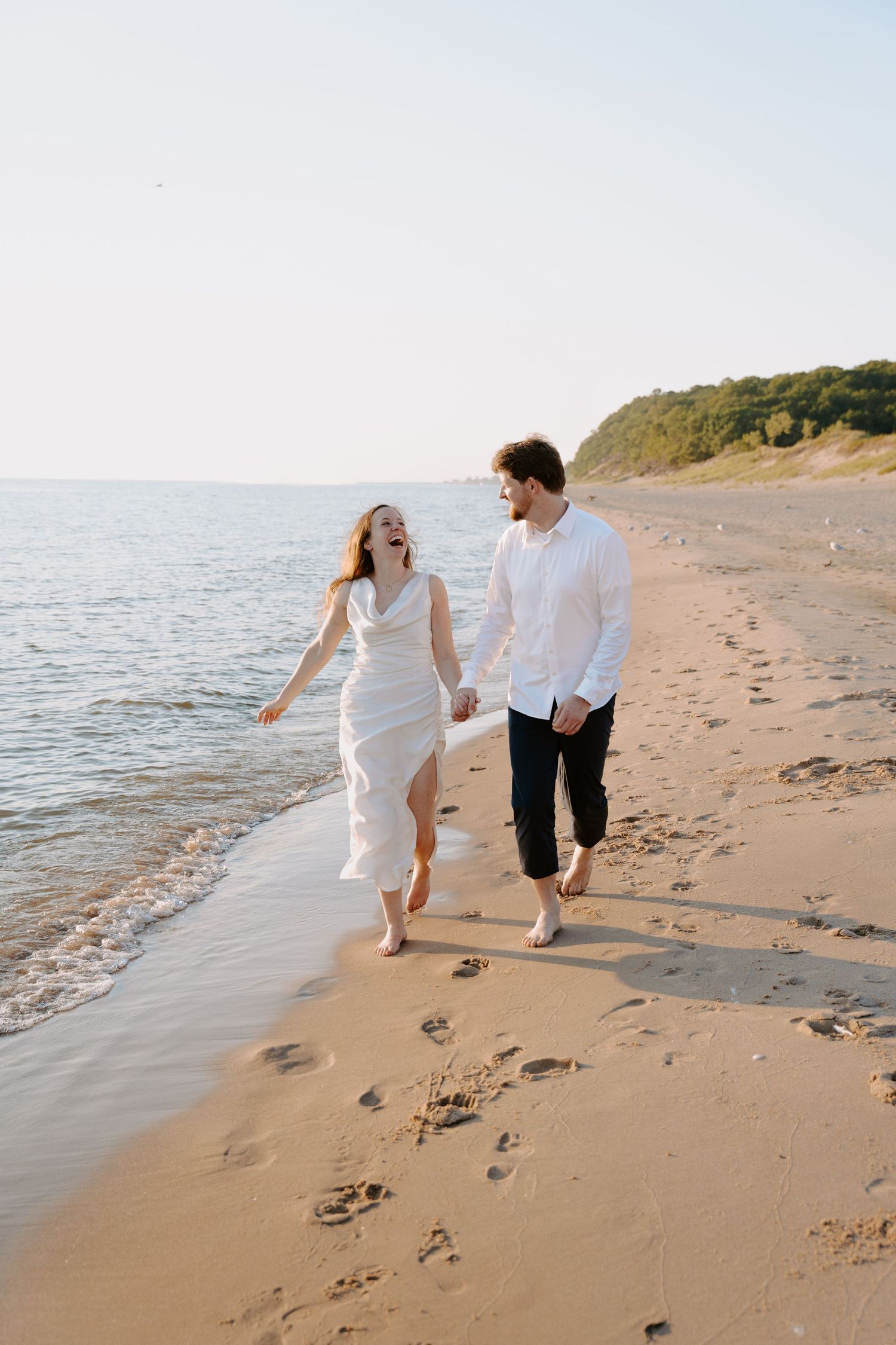 A playful couple runs along the beach leaving footprints in the sand.
