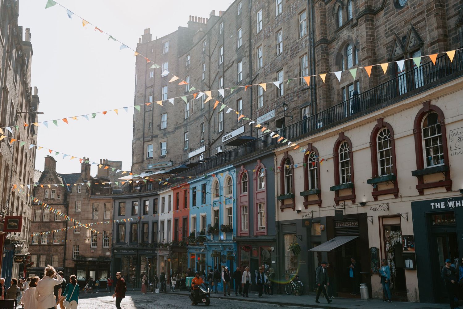 Historic Edinburgh street with traditional stone buildings and colorful bunting overhead.